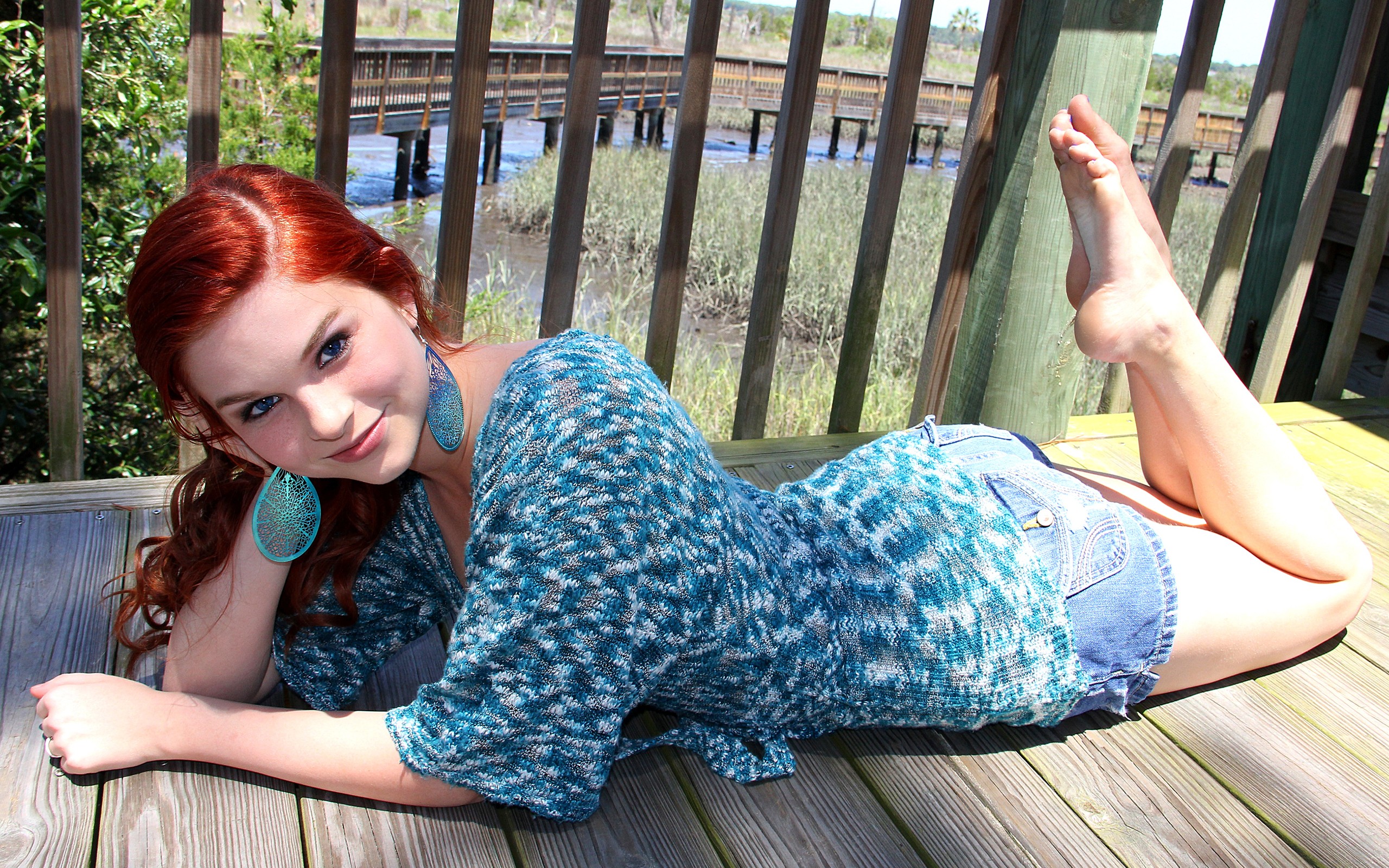 People 2560x1600 Karoline Kate model redhead blue eyes jean shorts barefoot women feet toes curled toes legs up bent legs feet in the air lying on front on the floor earring curly hair long hair hand on face foot sole smiling pointed toes looking at viewer women outdoors