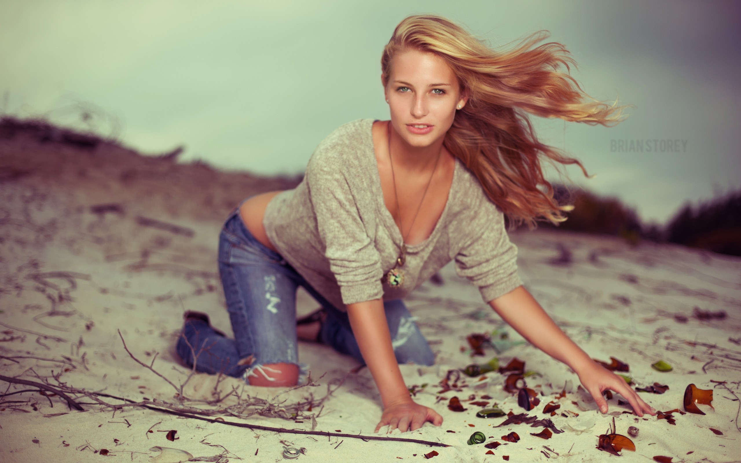 People 2560x1600 women jeans blonde sand model Brian Storey torn jeans cleavage long hair bent over sweatshirts women outdoors torn clothes windy looking at viewer sweater broken glass makeup