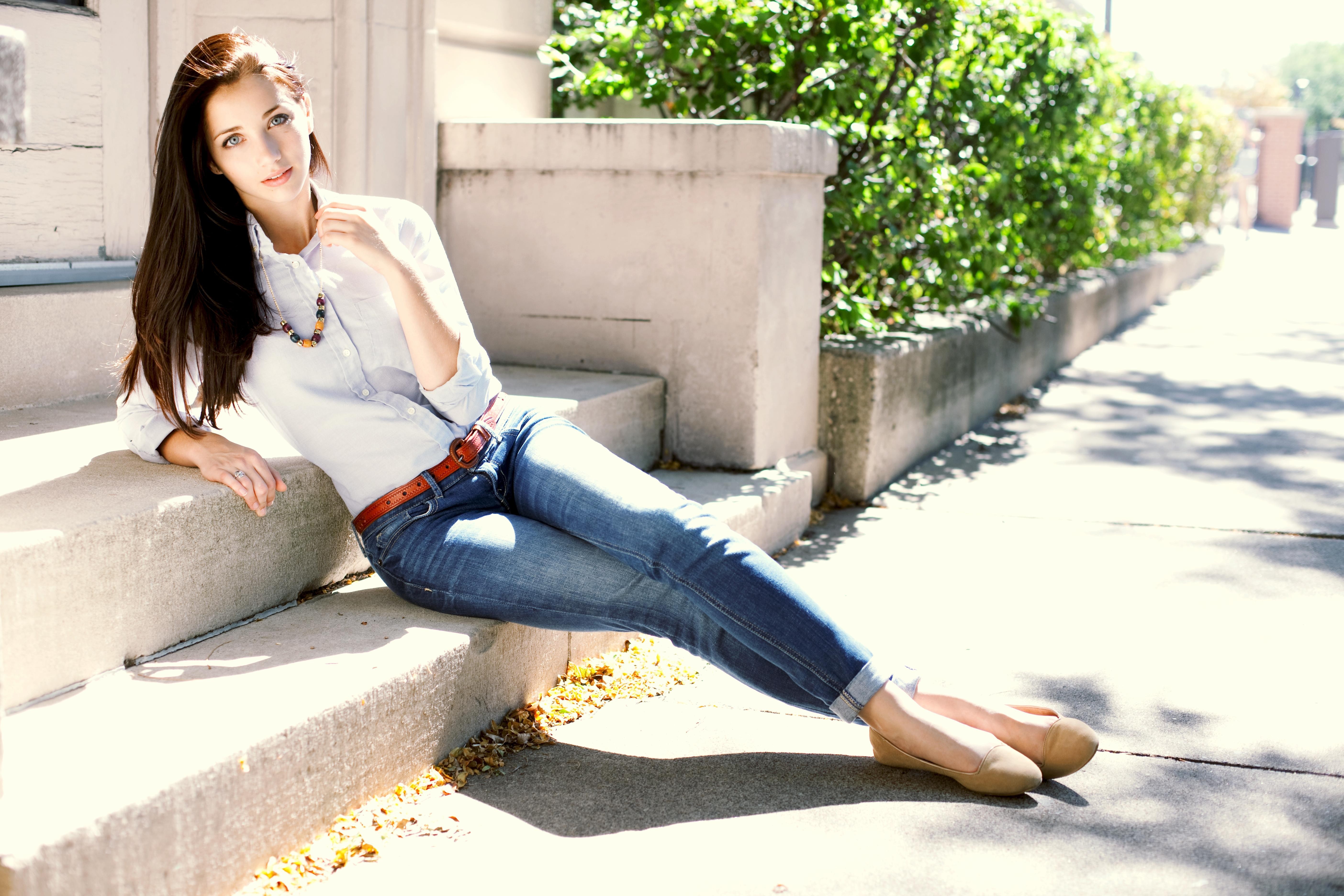 People 5616x3744 Emily Rudd women brunette blue eyes women outdoors jeans necklace long hair lying down white shirt belt looking at viewer pale urban legs together