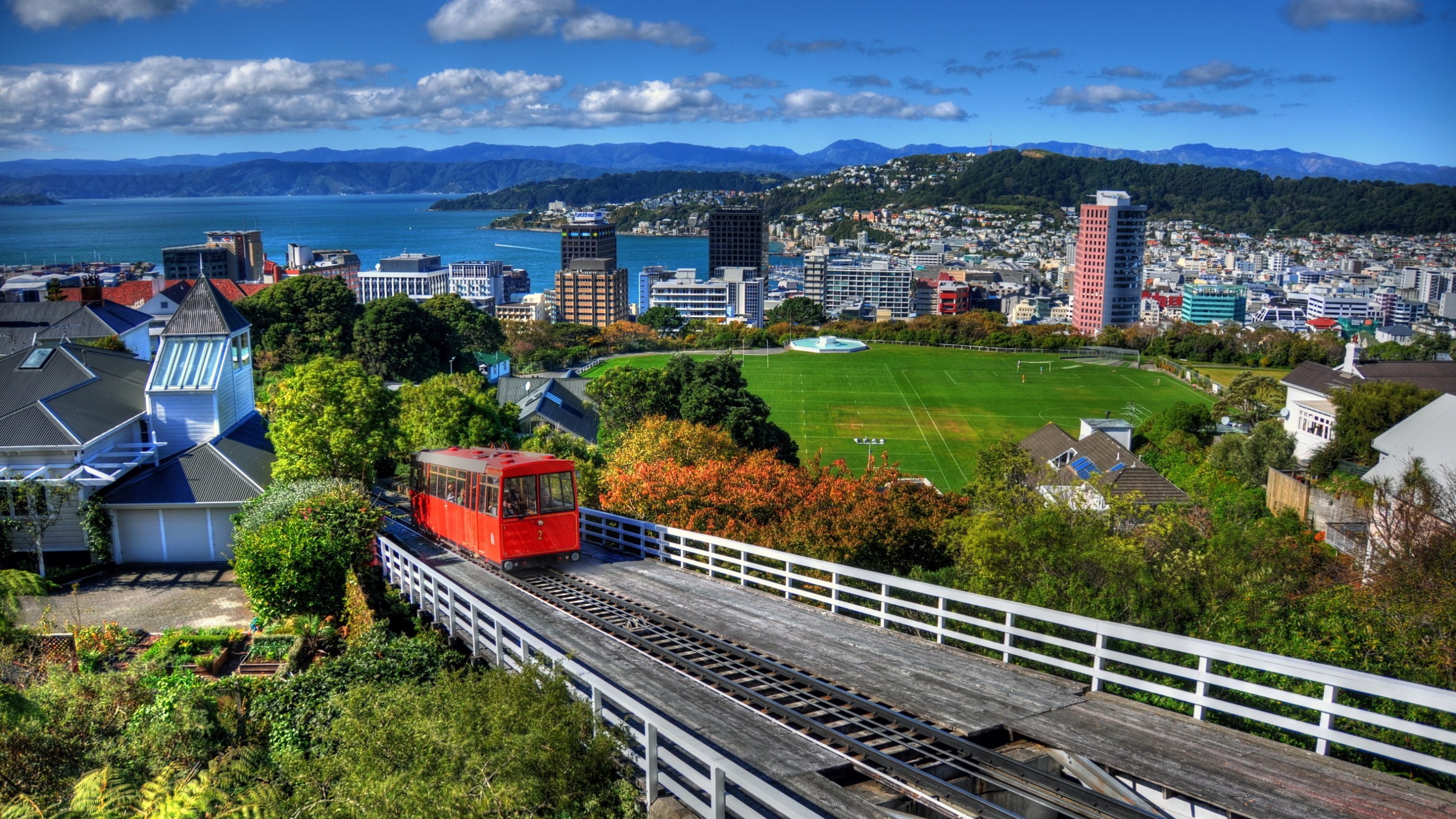 General 2560x1440 architecture building Wellington New Zealand city cityscape train hills soccer field clouds house trees sea railway grass vehicle