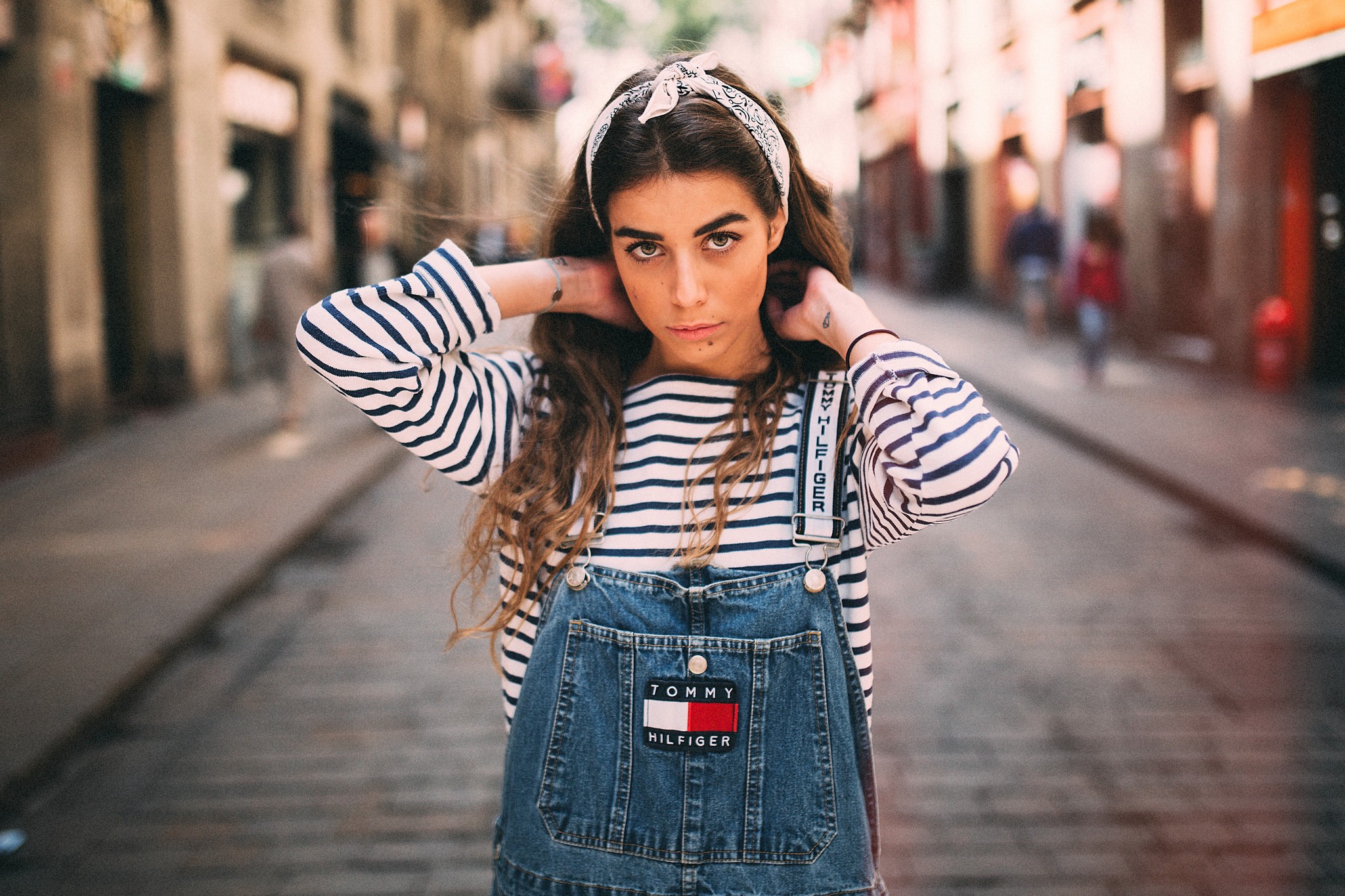 People 2048x1365 women Robert Marcillas Ronda brunette headband striped clothing overalls street looking at viewer hands in hair tattoo wavy hair long hair moles thick eyebrows urban women outdoors Tommy Hilfiger