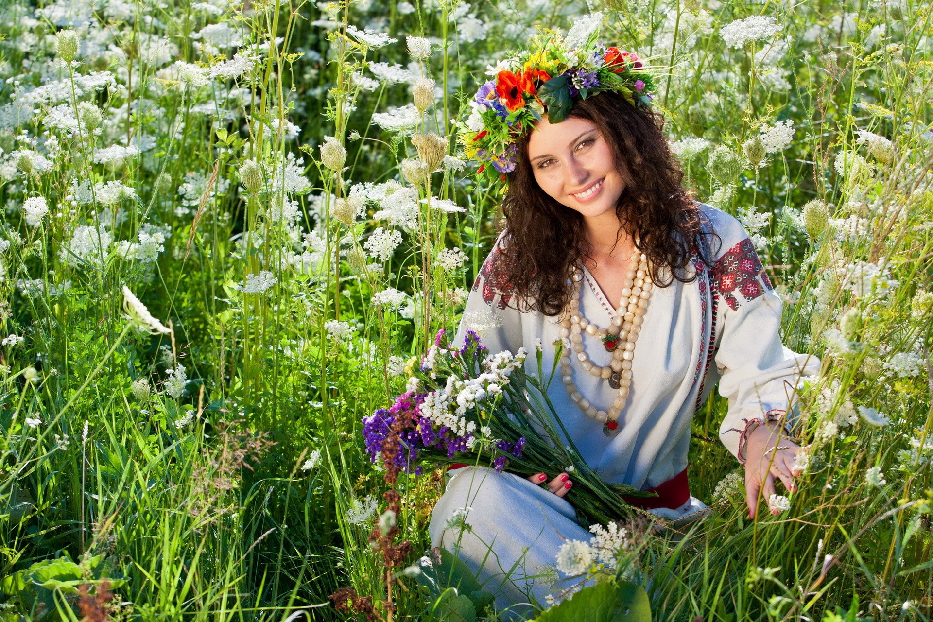 People 1920x1280 women model brunette women outdoors flowers nature field flower in hair curly hair wreaths plants looking at viewer smiling flower crown traditional clothing Russian