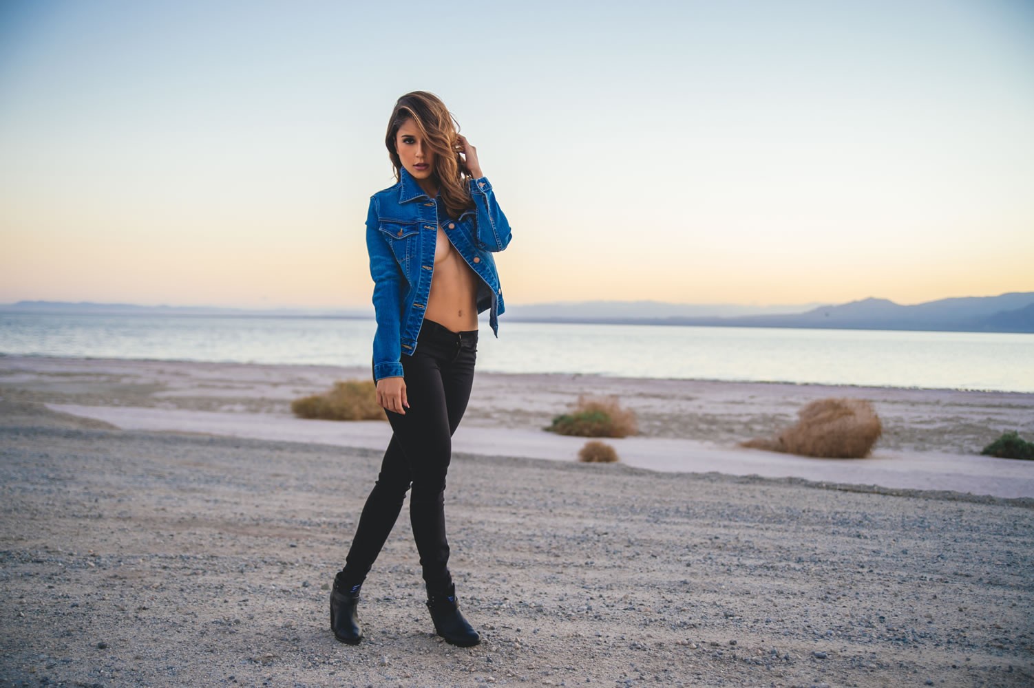 People 1502x1000 women women outdoors beach brunette denim Tianna Gregory women on beach denim jacket black pants hair in face long hair standing blue jacket touching hair black boots no bra strategic covering covering boobs public smoky eyes dark eyes hands on knees open clothes legs crossed looking at viewer