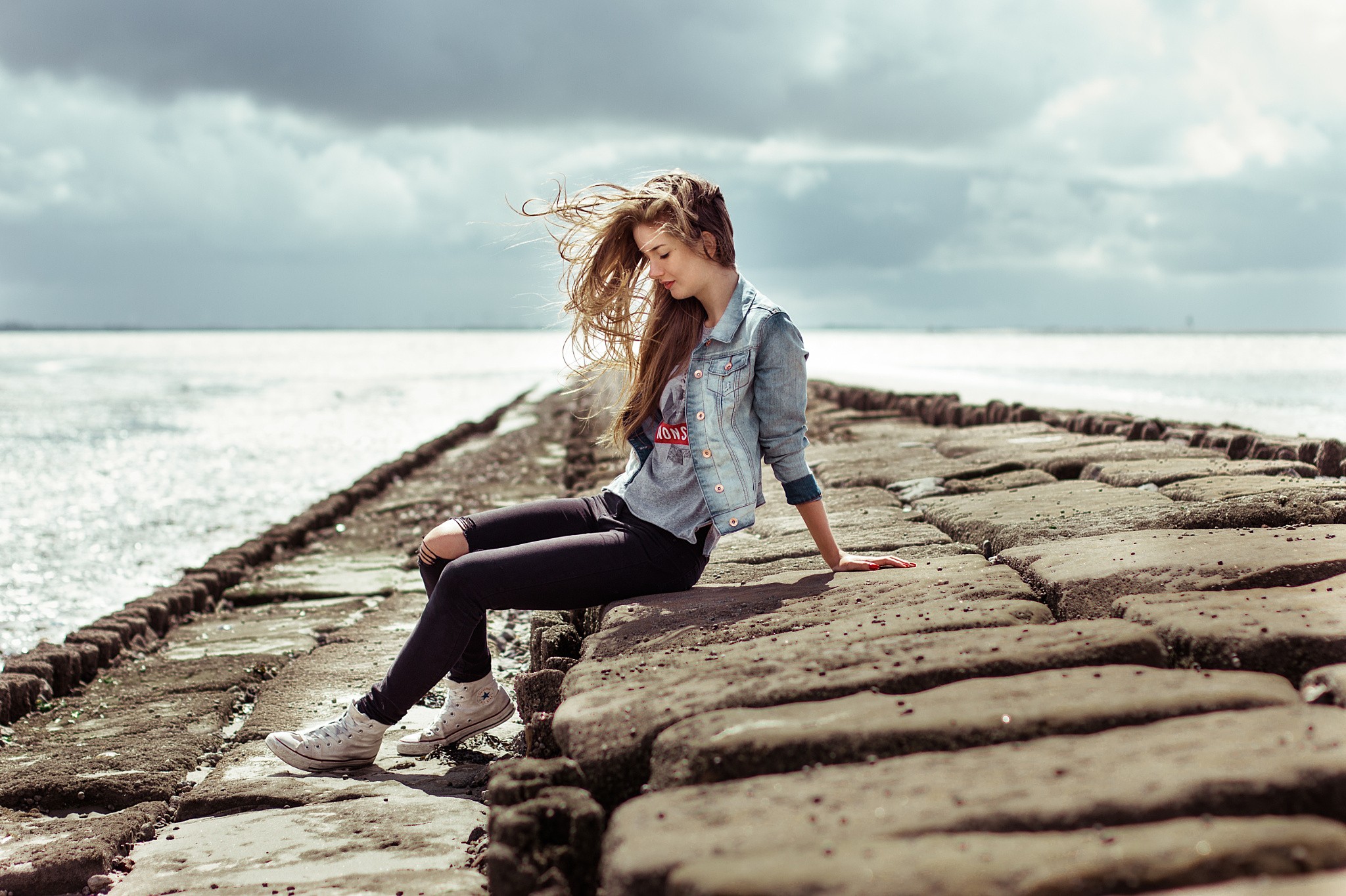 People 2048x1365 women sitting sneakers closed eyes sea torn jeans jeans sky torn clothes windy women outdoors outdoors model long hair brunette Converse