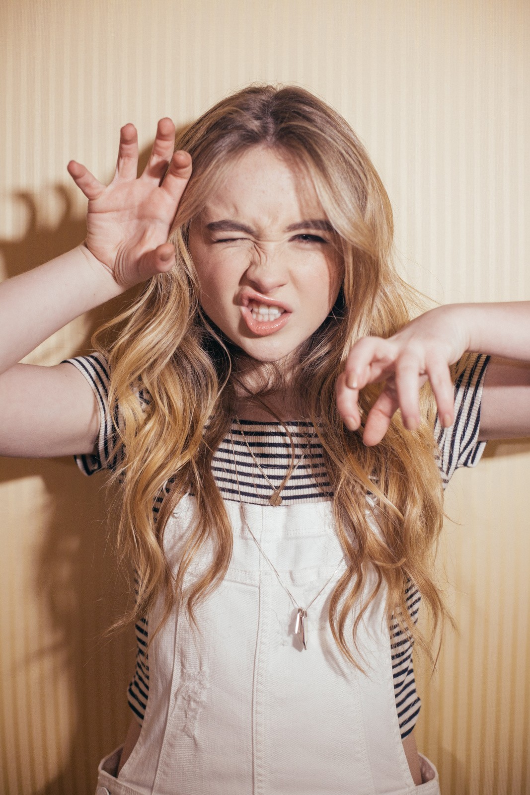 People 1067x1600 Sabrina Carpenter women blonde long hair face hand gesture overalls striped tops American women actress singer women indoors striped clothing one eye closed looking at viewer portrait display