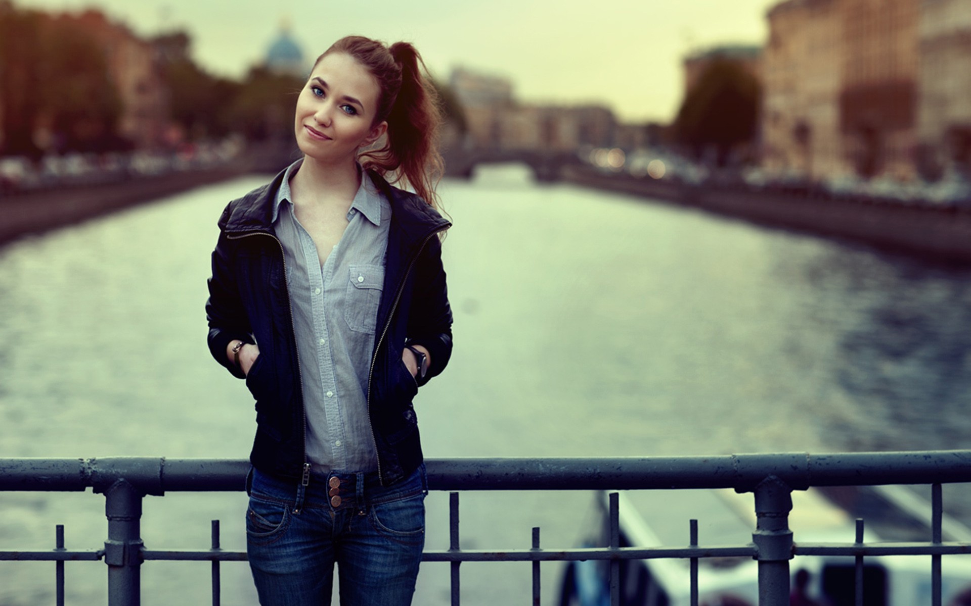 People 1920x1200 women women outdoors jeans ponytail depth of field urban smiling cityscape river model leather jacket hands in pockets blue shirt standing looking at viewer