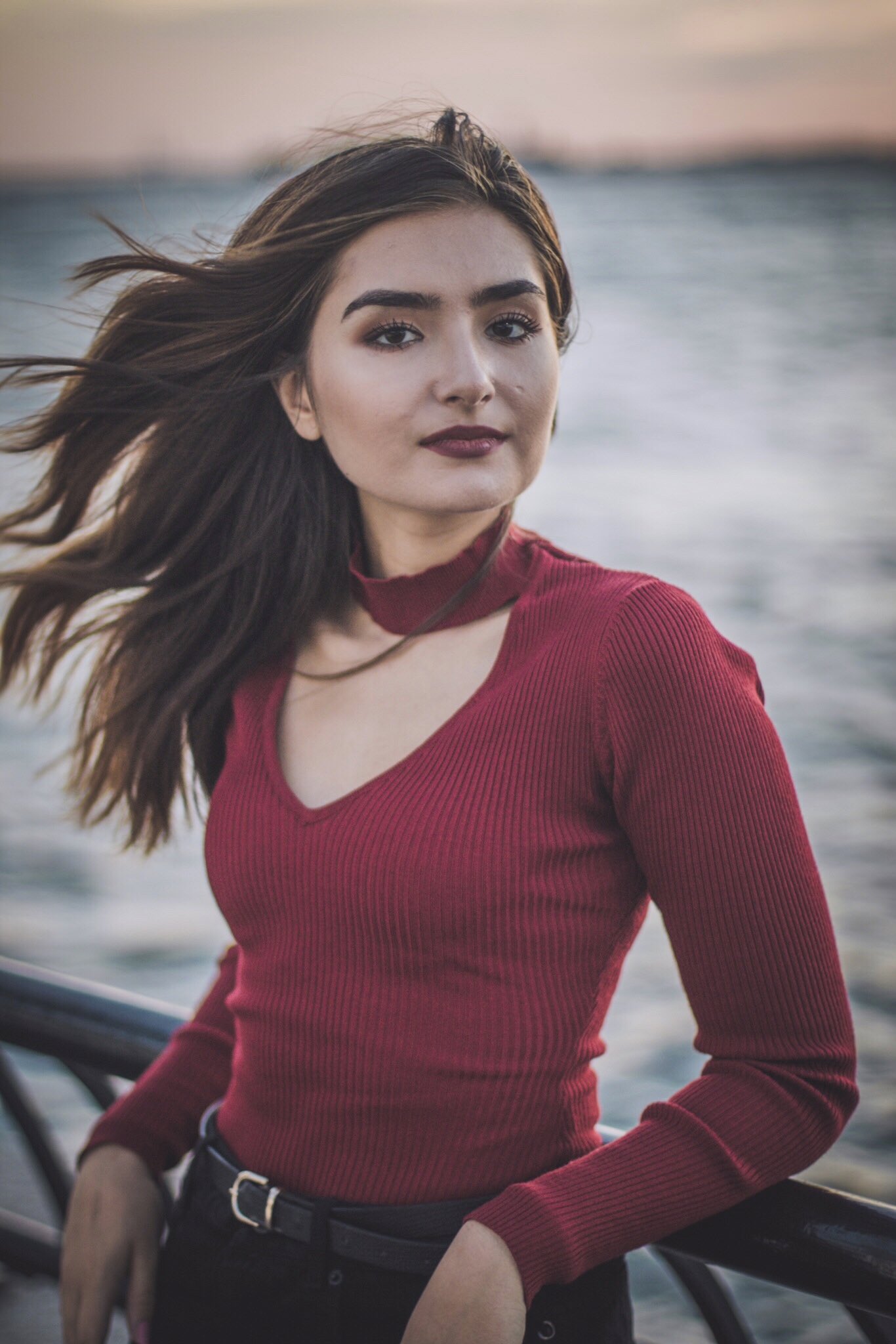 People 1366x2048 women model long hair brunette straight hair hair blowing in the wind looking at viewer women outdoors bokeh portrait display water sea horizon tight clothing red tops shirt red shirt belt black belt leaning collar lipstick red lipstick dark eyes