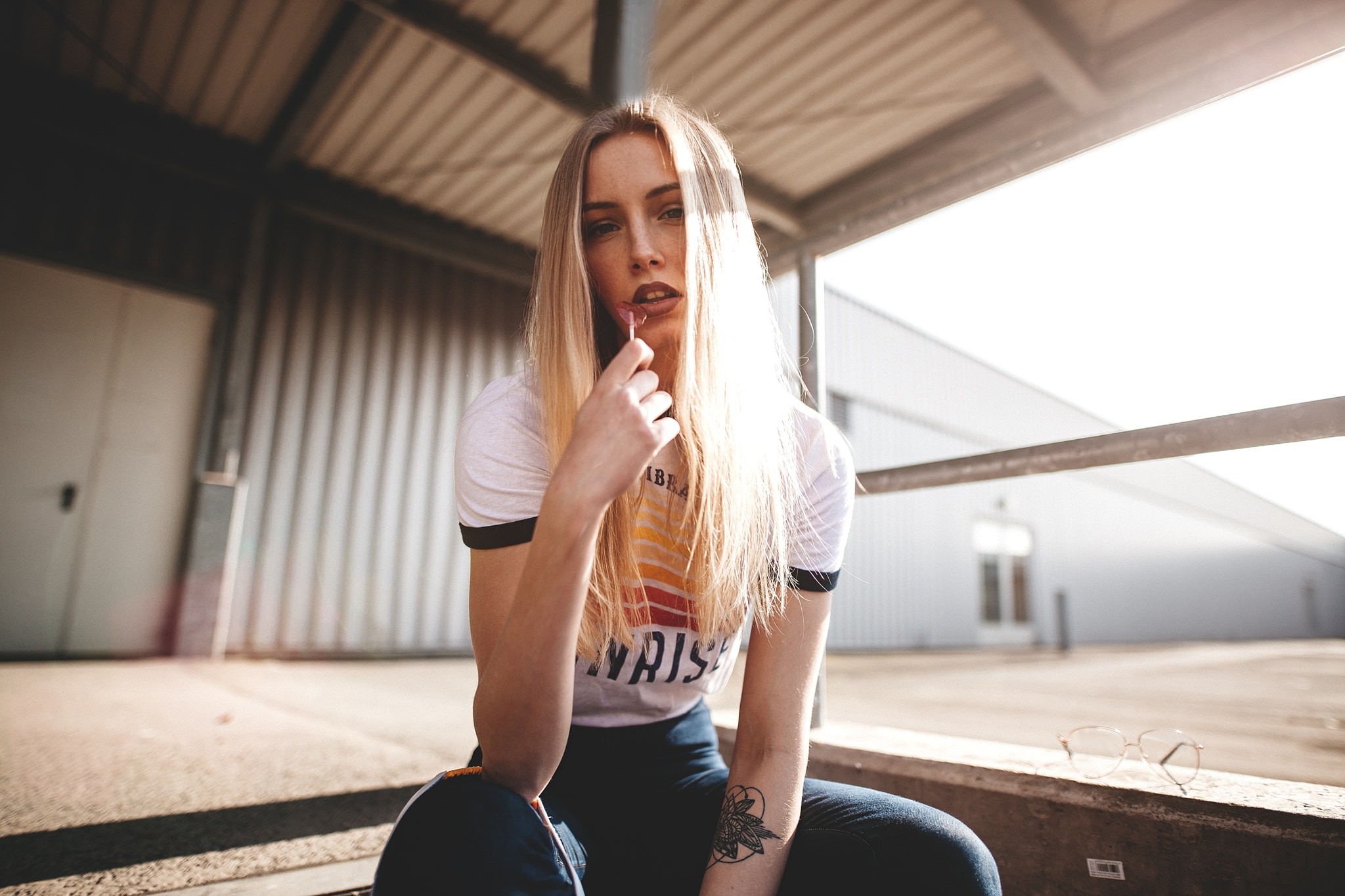 People 2048x1365 women blonde portrait T-shirt lollipop sitting tattoo brown eyes open mouth white shirt looking at viewer frontal view