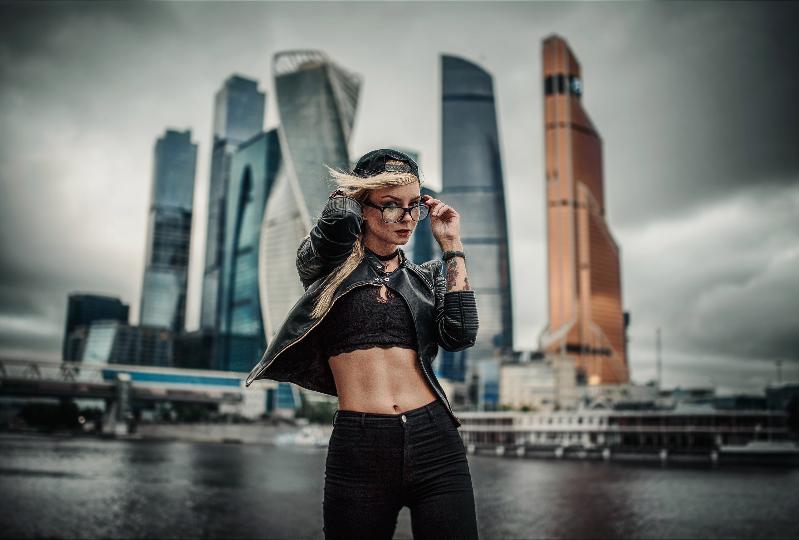 People 2560x1730 Hakan Erenler women model portrait outdoors looking at viewer depth of field water sky city building blonde women with glasses leather jacket short tops black top jeans belly belly button baseball cap necklace tattoo women outdoors urban