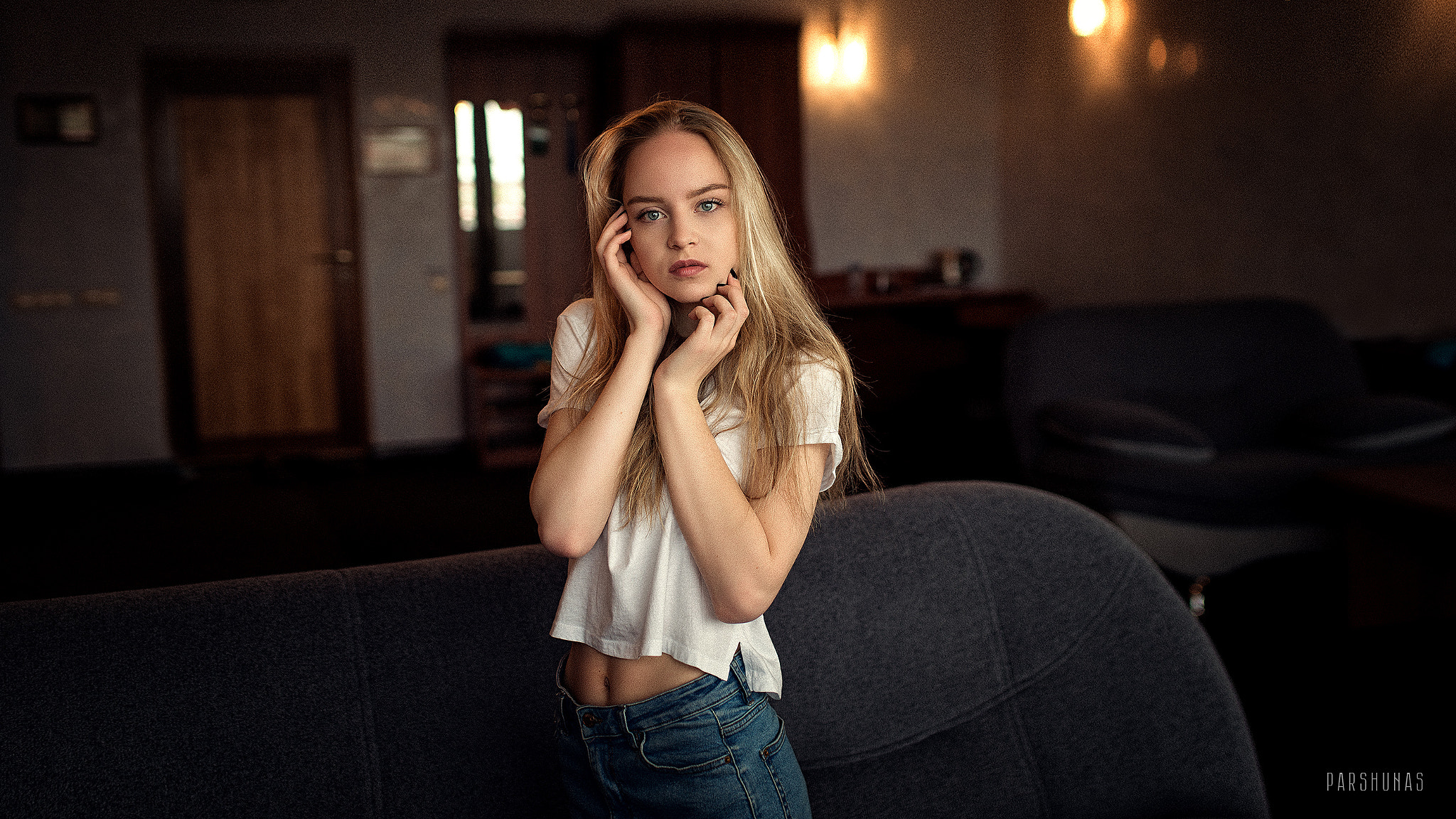 People 2048x1152 women Anton Parshunas blonde blue eyes hand on face white shirt jeans denim couch looking at viewer touching face watermarked