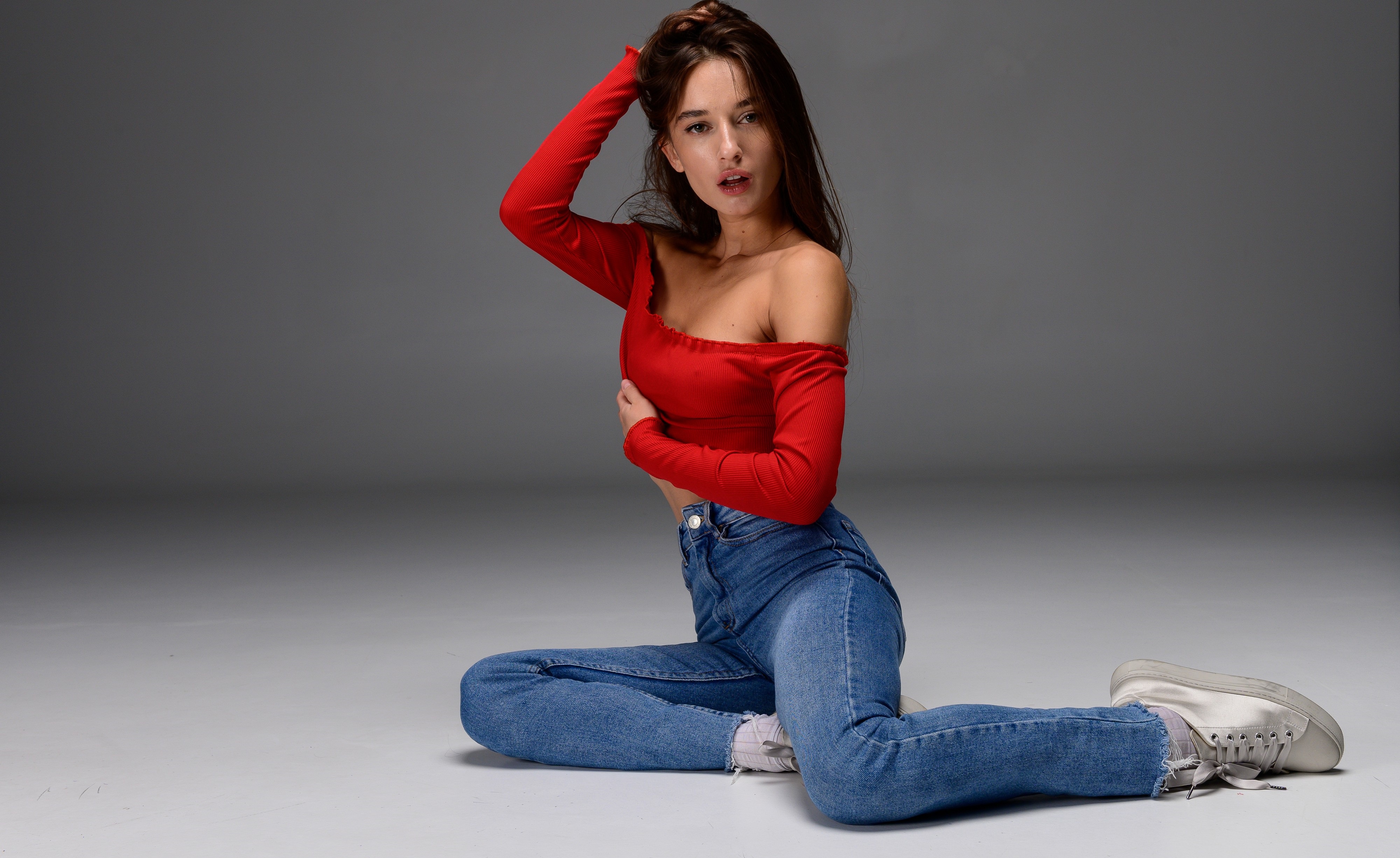 People 4000x2452 red lipstick hands in hair cleavage red t-shirt jeans shoes sitting on the floor open mouth studio Gloria Sol Heal-Fit whole body off shoulder collarbone looking at viewer teeth simple background women model