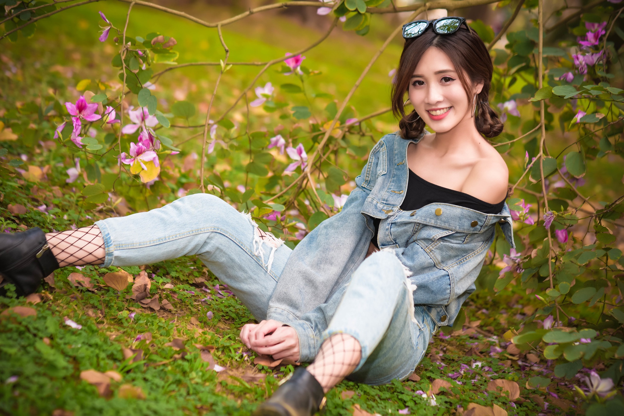 People 2048x1367 Asian women model long hair brunette depth of field jeans jacket black top earring sunglasses twintails black boots fishnet stockings sitting grass flowers bushes leaves looking at viewer