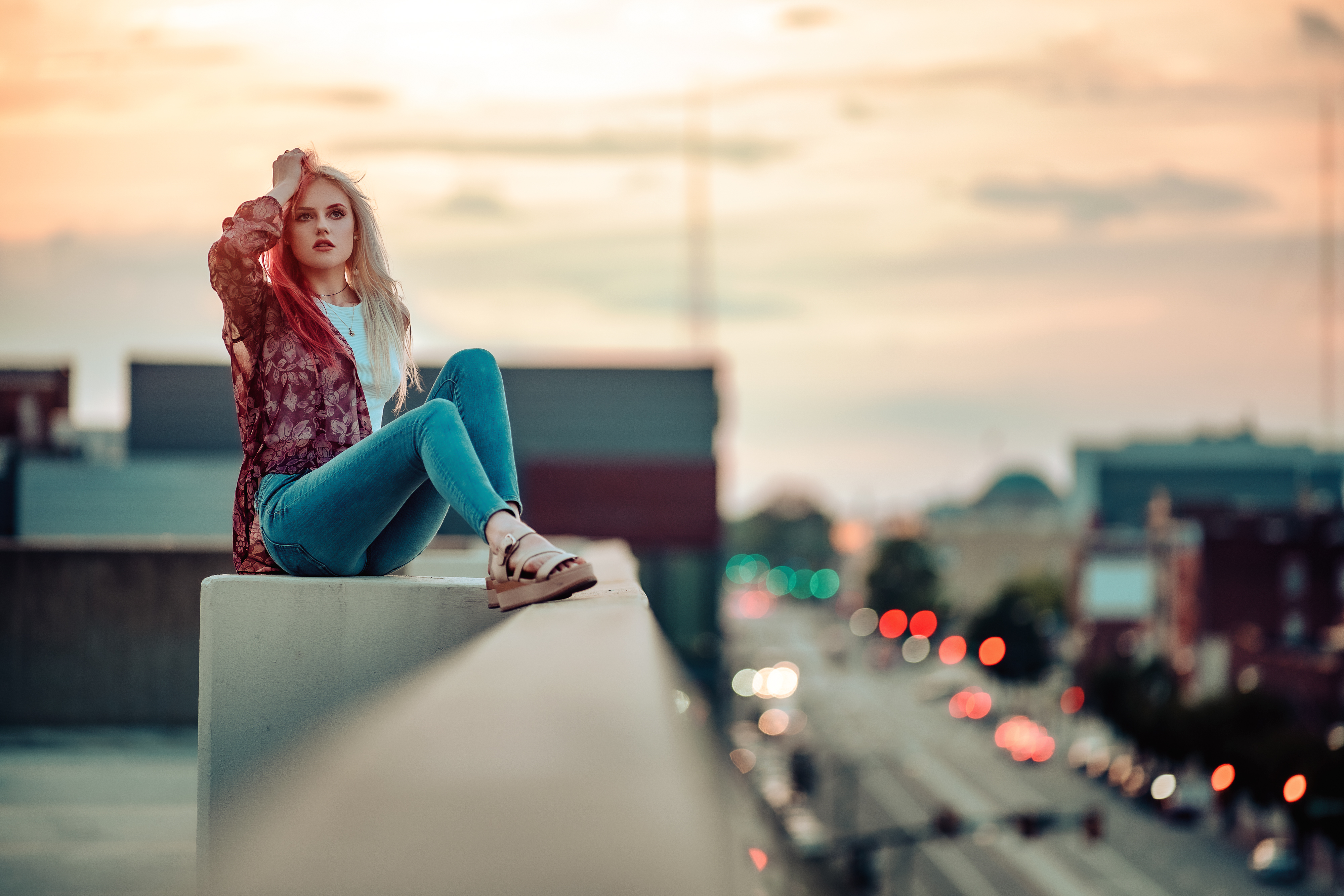 People 4000x2667 women portrait model blonde brown eyes white shirt jeans denim sandals sitting hands in hair arms up dyed hair red lipstick rooftops traffic lights depth of field bokeh sunset