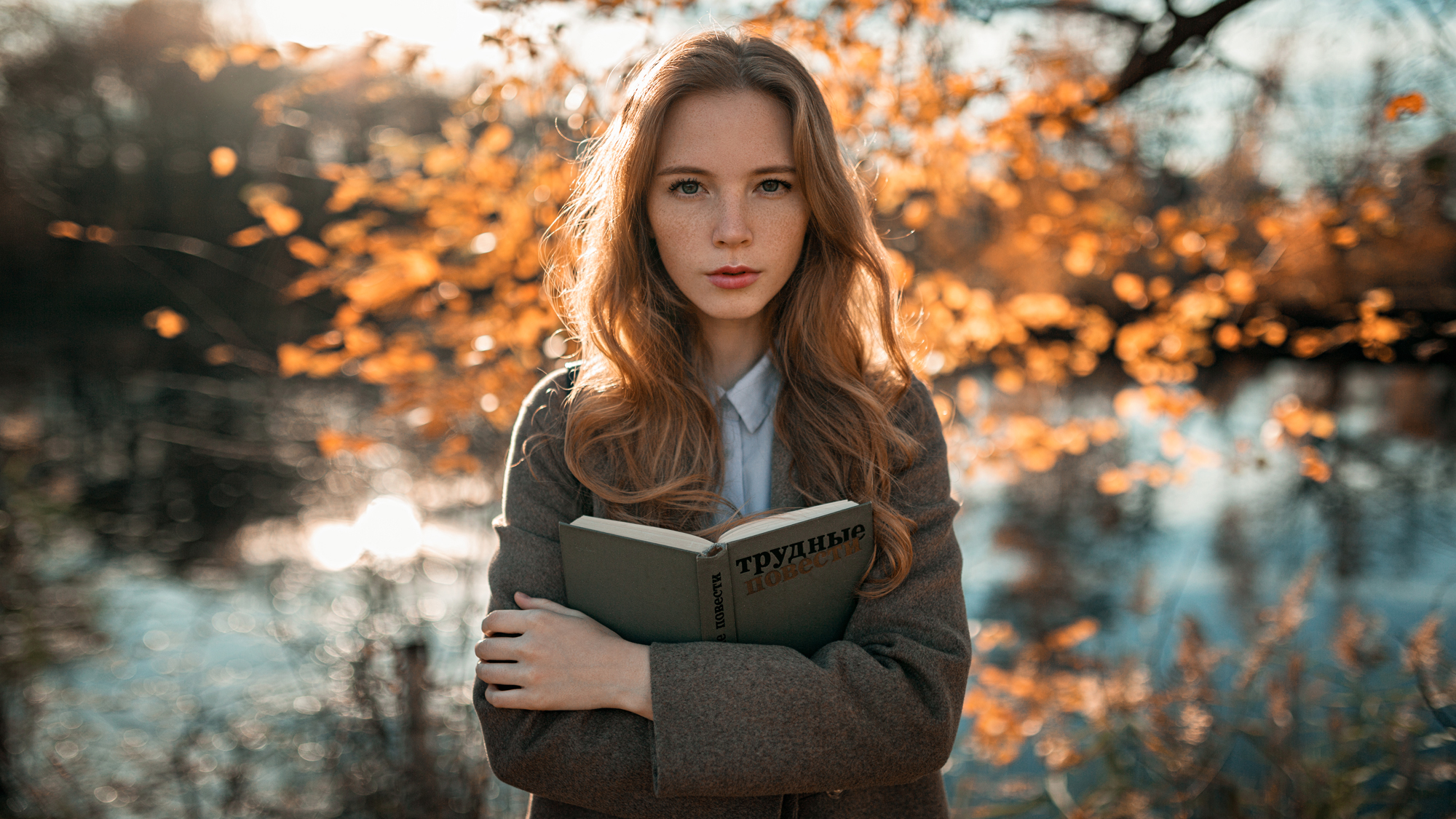 People 2000x1125 women model redhead long hair looking at viewer outdoors freckles coats books forest trees fall water backlighting lake sunset sunlight depth of field arms crossed women outdoors Aleksandr Kurennoi Russian grey coat blue shirt Anastasia