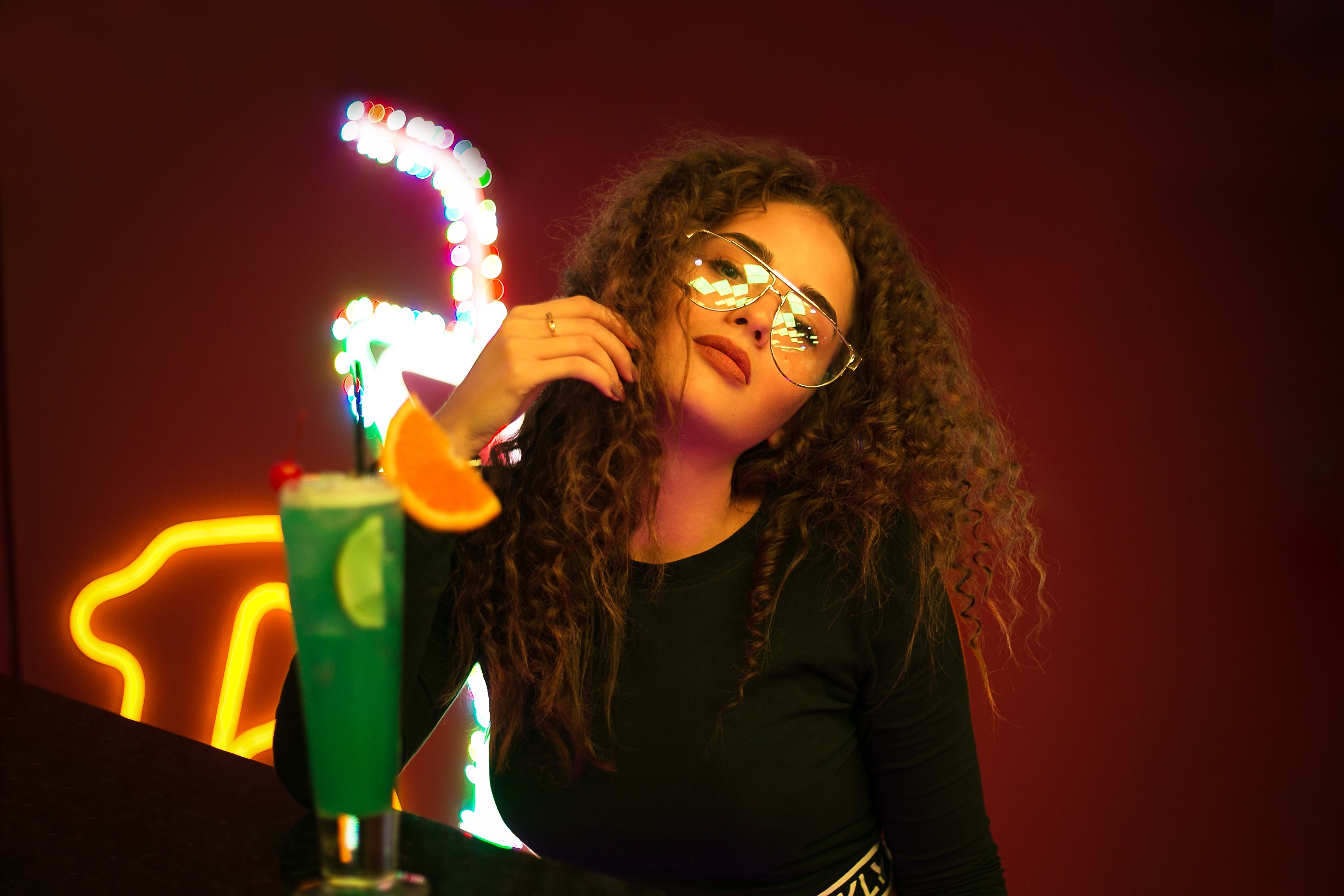 People 2450x1633 women model brunette curly hair indoors women with glasses glasses drink drinking glass looking at viewer bokeh black top lights neon women indoors portrait