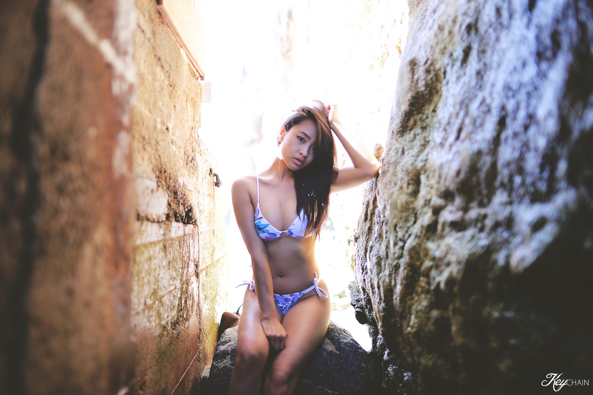People 2048x1367 Christy Truong women Asian model bikini brunette pierced navel sitting hands on head wall rocks looking at viewer women outdoors belly arms up outdoors