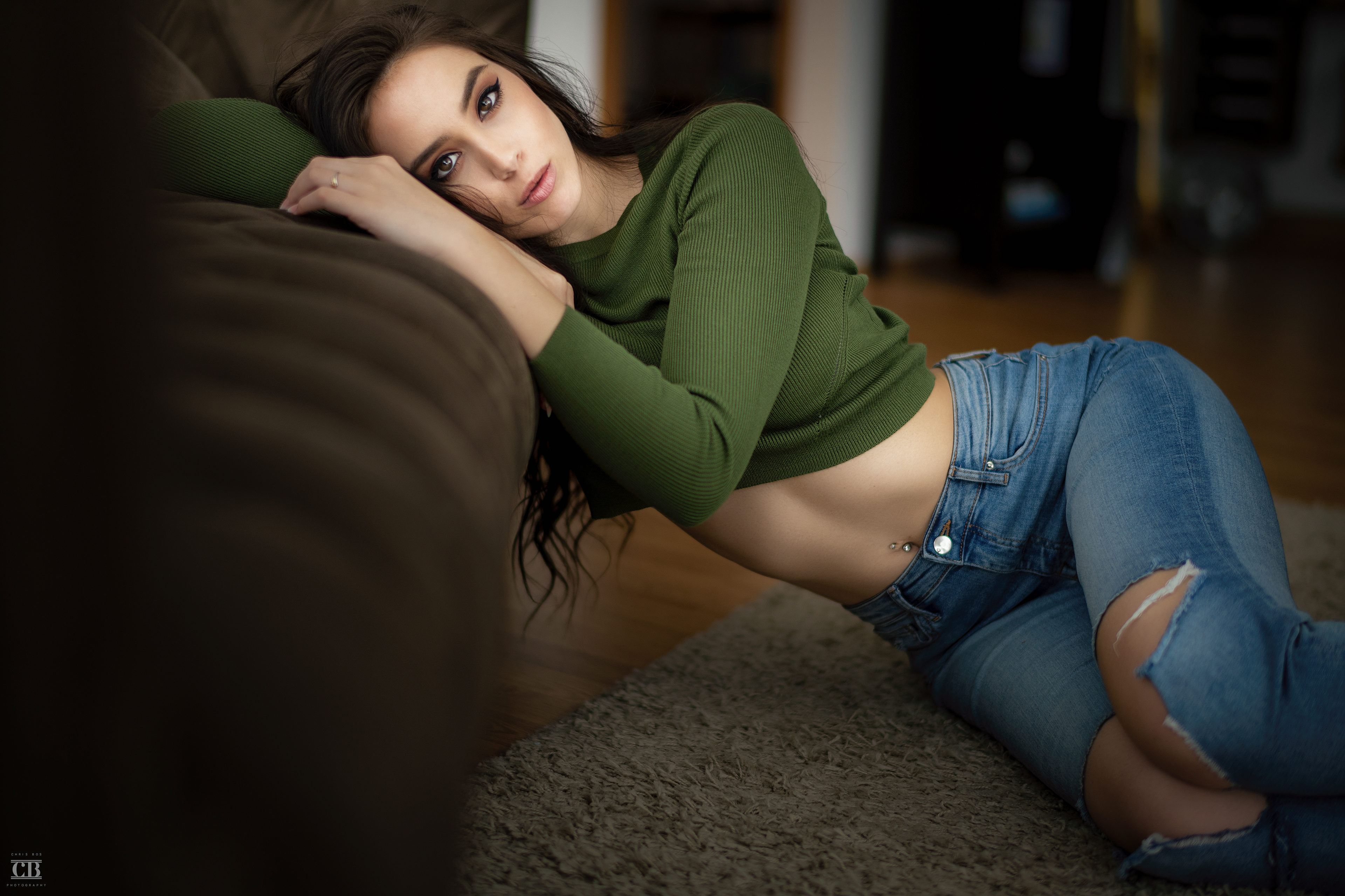 People 3840x2560 Anna Bous women brunette model long hair looking at viewer crop top sweater jeans torn jeans belly pierced navel lying on side on the floor couch depth of field brown eyes indoors women indoors Christopher Leone torn clothes green sweater blue  jeans blue pants