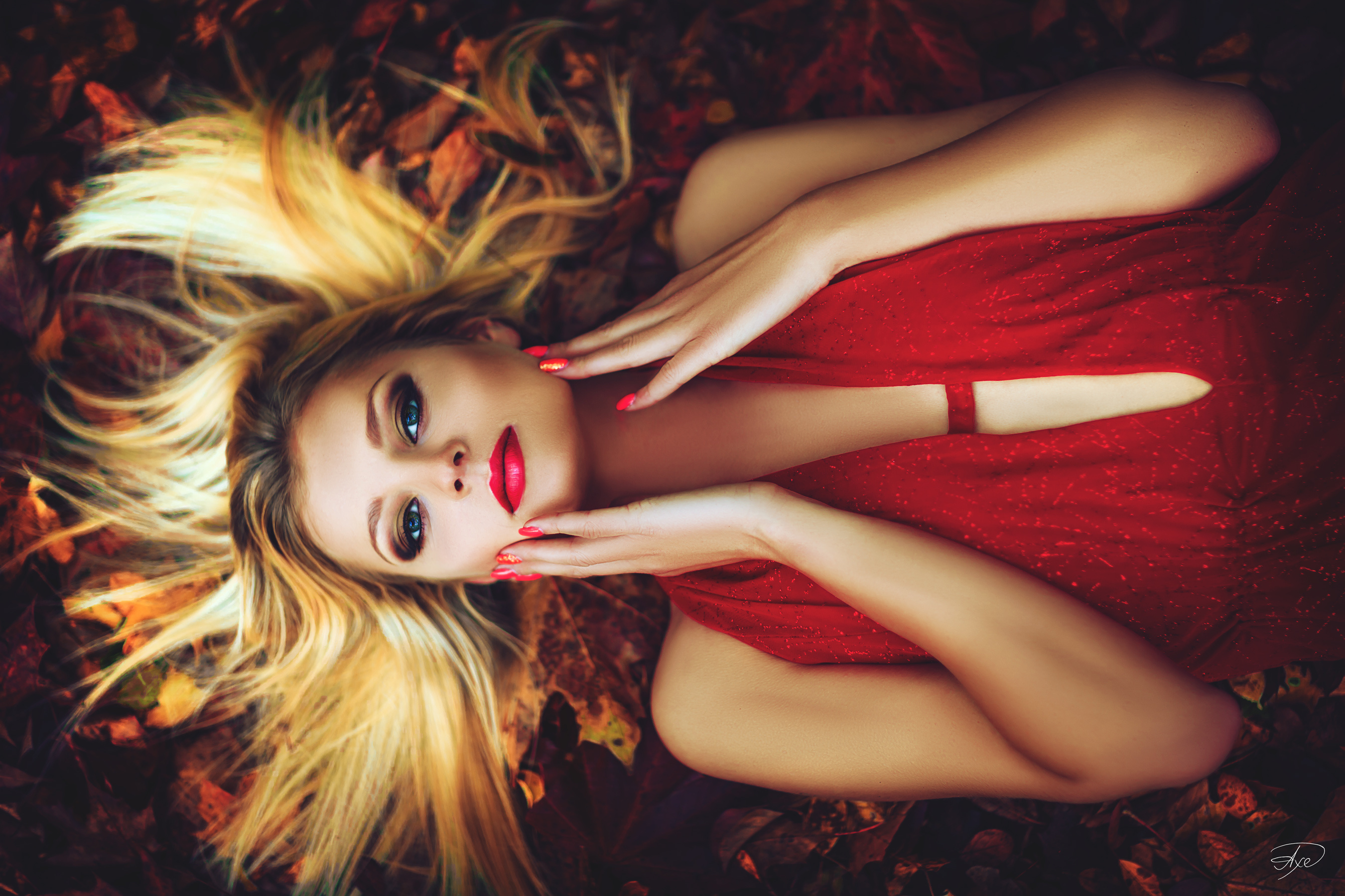 People 2700x1800 women model blonde long hair straight hair dyed hair long nails red nails painted nails looking at viewer lying on back women outdoors leaves red dress blue eyes touching face watermarked bare shoulders red lipstick colorful