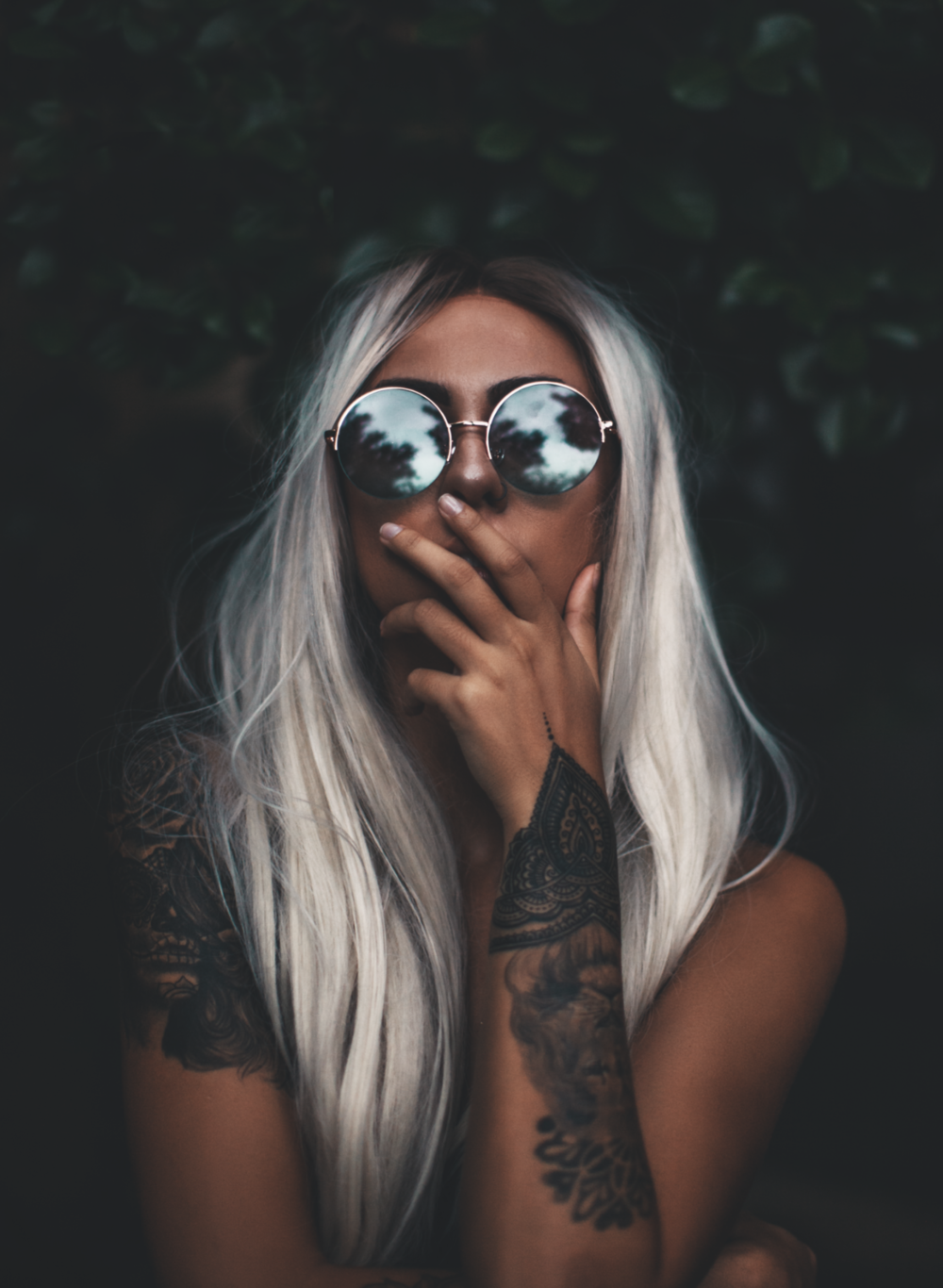 People 1000x1366 women model blonde dyed hair long hair straight hair touching face glasses women with glasses portrait display simple background reflection nature bokeh tattoo natural light covering mouth leaves dark background skinny women outdoors