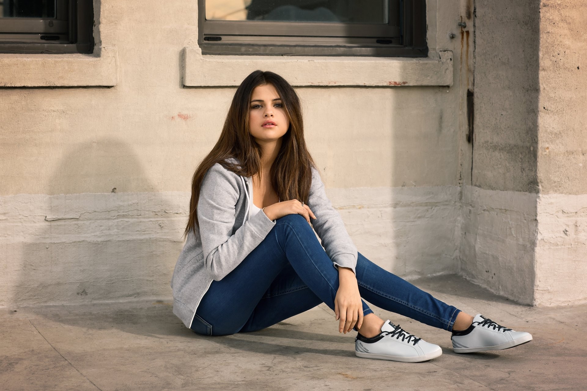 People 1920x1280 celebrity Selena Gomez brunette jeans brown eyes women blue  jeans blue pants tight pants long hair white sneakers blouses young women sitting American women wall hands on knees straight hair sneakers hand on leg open mouth solo