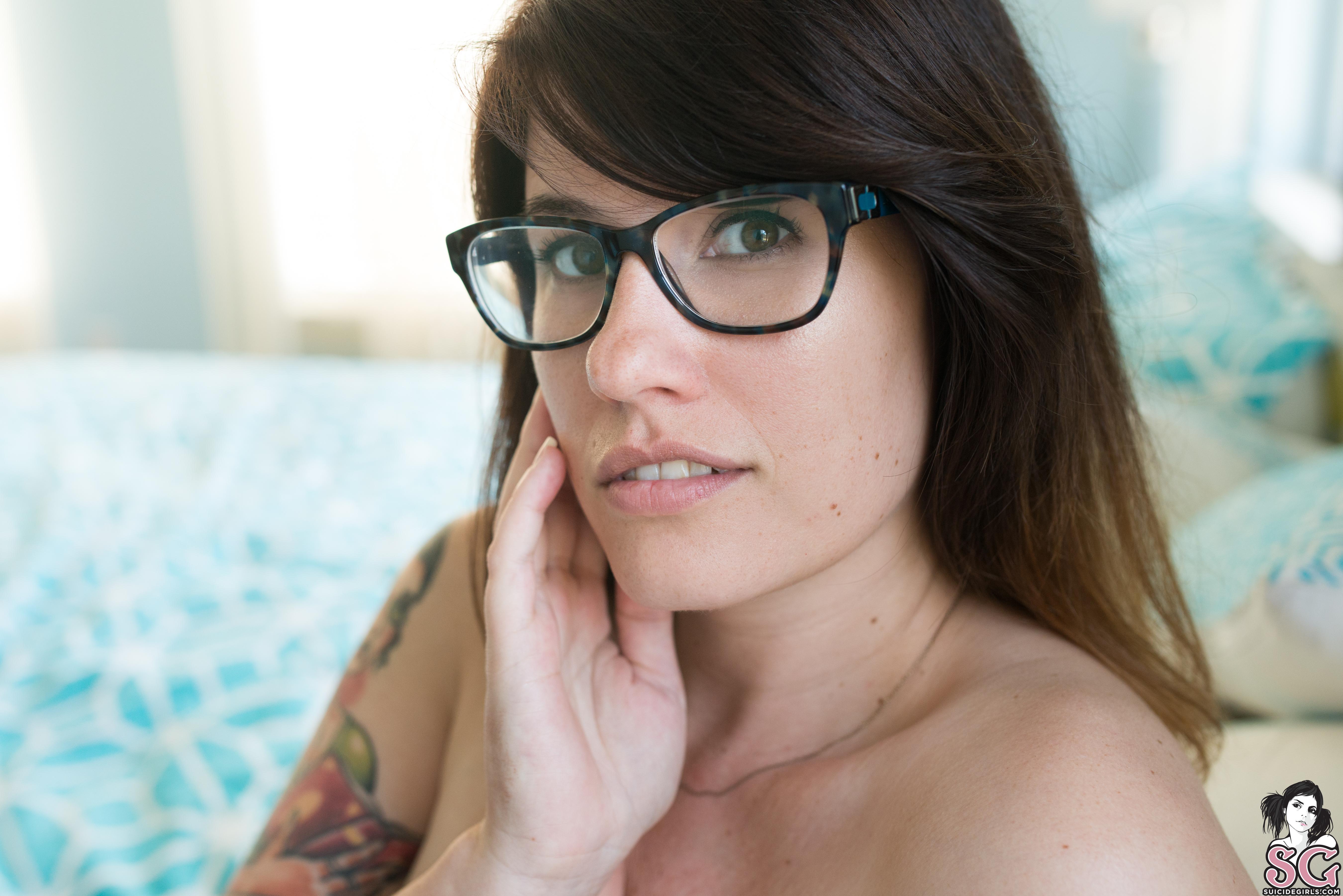 People 5400x3603 brunette Suicide Girls in bed bedroom Prettyneurotic Suicide women closeup watermarked parted lips women with glasses glasses looking at viewer long hair hand on face depth of field teeth tattoo pillow