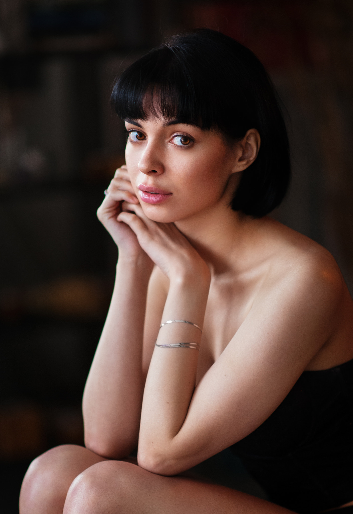 People 1408x2048 Maxim Maximov women Tania Frost dark hair short hair bangs looking at viewer bare shoulders dress black clothing depth of field bracelets portrait side view resting head knees together portrait display low light