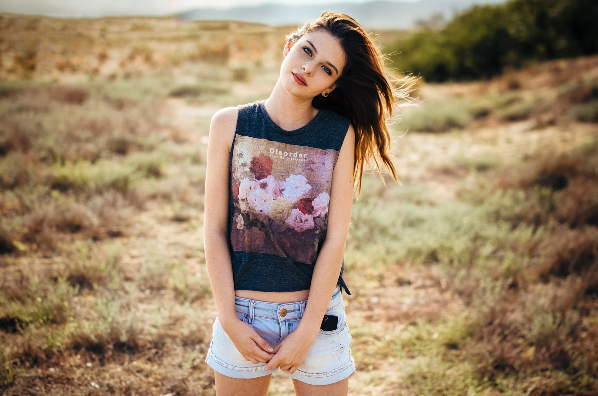 People 2048x1356 women model long hair brunette portrait looking at viewer blue eyes T-shirt belly jean shorts cellphone field streched ears freckles depth of field outdoors women outdoors Gustavo Terzaghi pale blue shorts