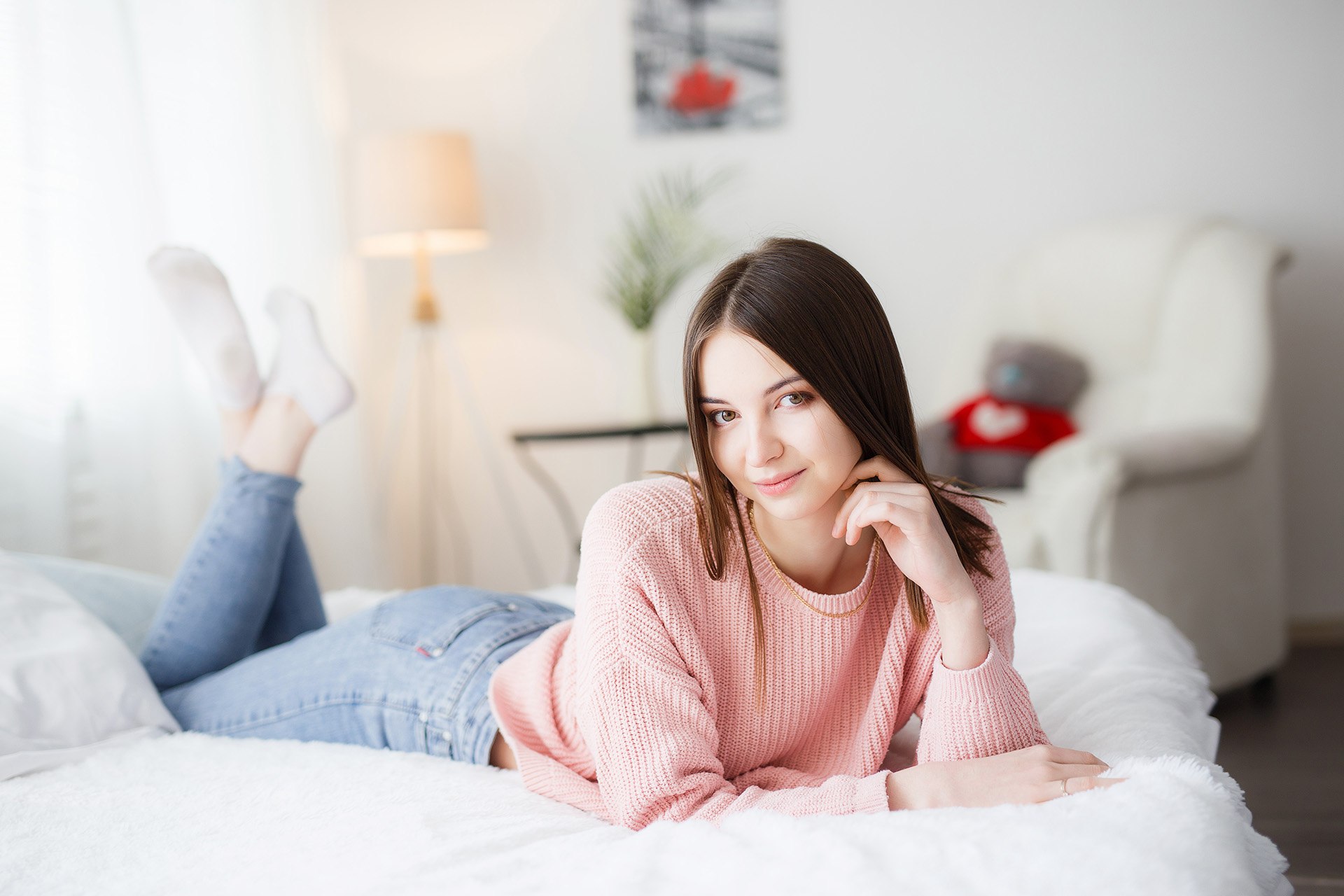 People 1920x1280 women model portrait indoors bed looking at viewer lying on front in bed jeans socks sweater depth of field feet in the air brunette smiling women indoors bedroom pink sweater touching face legs up young women