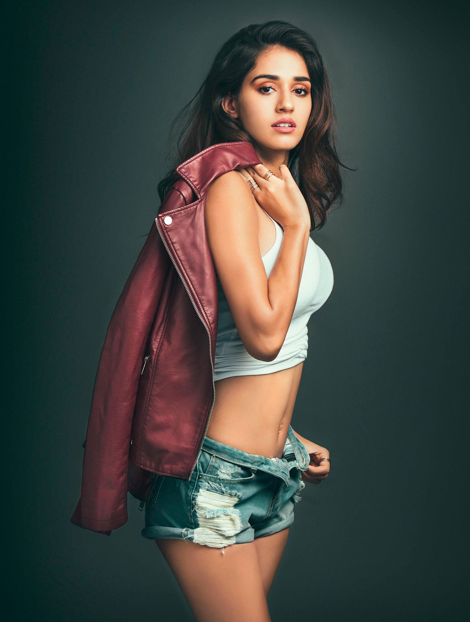 People 1500x1984 Disha Patani women actress model Bollywood actresses Bollywood Indian brunette long hair simple background legs jean shorts short shorts torn jeans holding jacket red jackets open shorts dark hair blue shorts blue pants standing