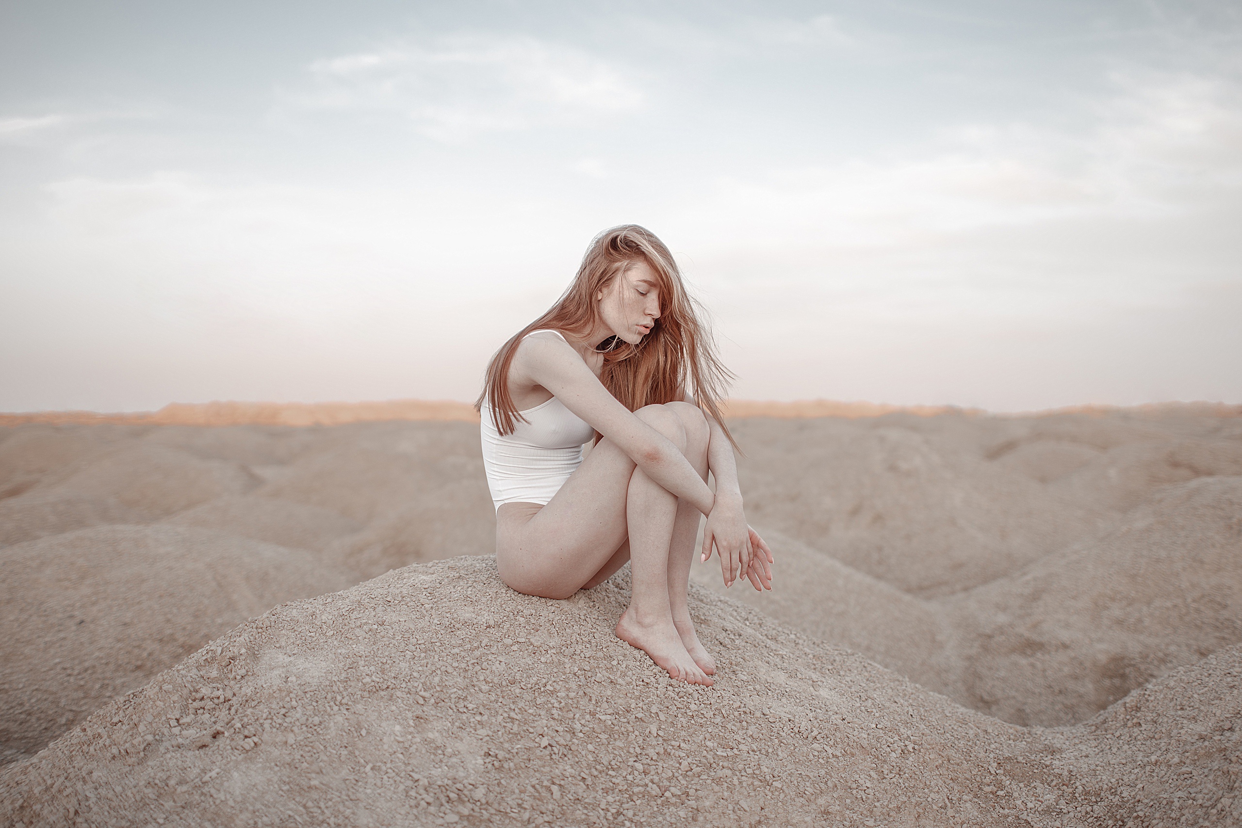 People 2560x1707 women model women outdoors long hair closed eyes whole body holding knees bent legs holding legs side view on the ground horizon white bodysuit outdoors parted lips thighs together knees together sitting legs together barefoot