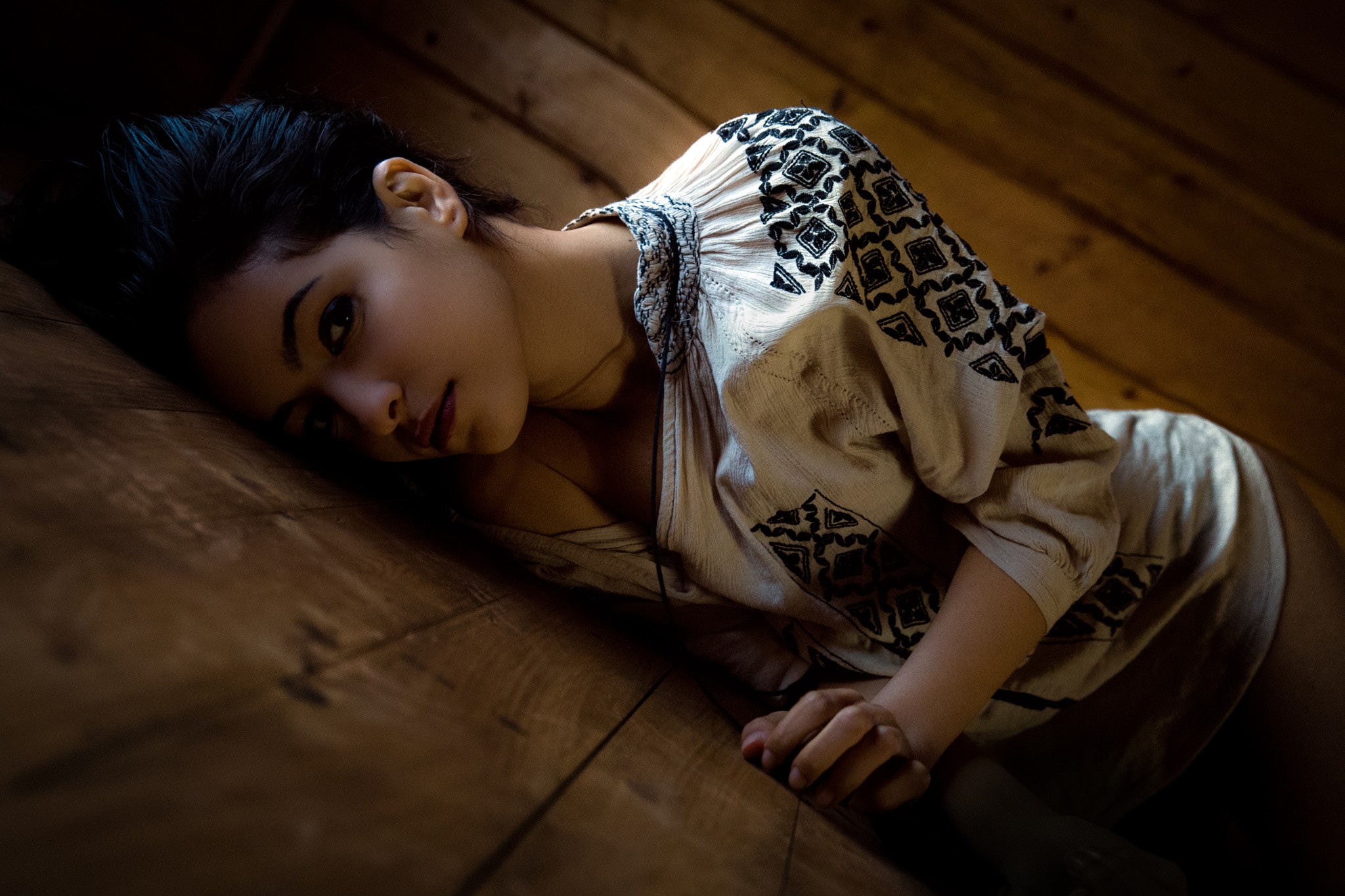 People 2048x1365 women dark eyes face lying on side hips black hair looking at viewer women indoors indoors model makeup wooden surface Amine Fassi