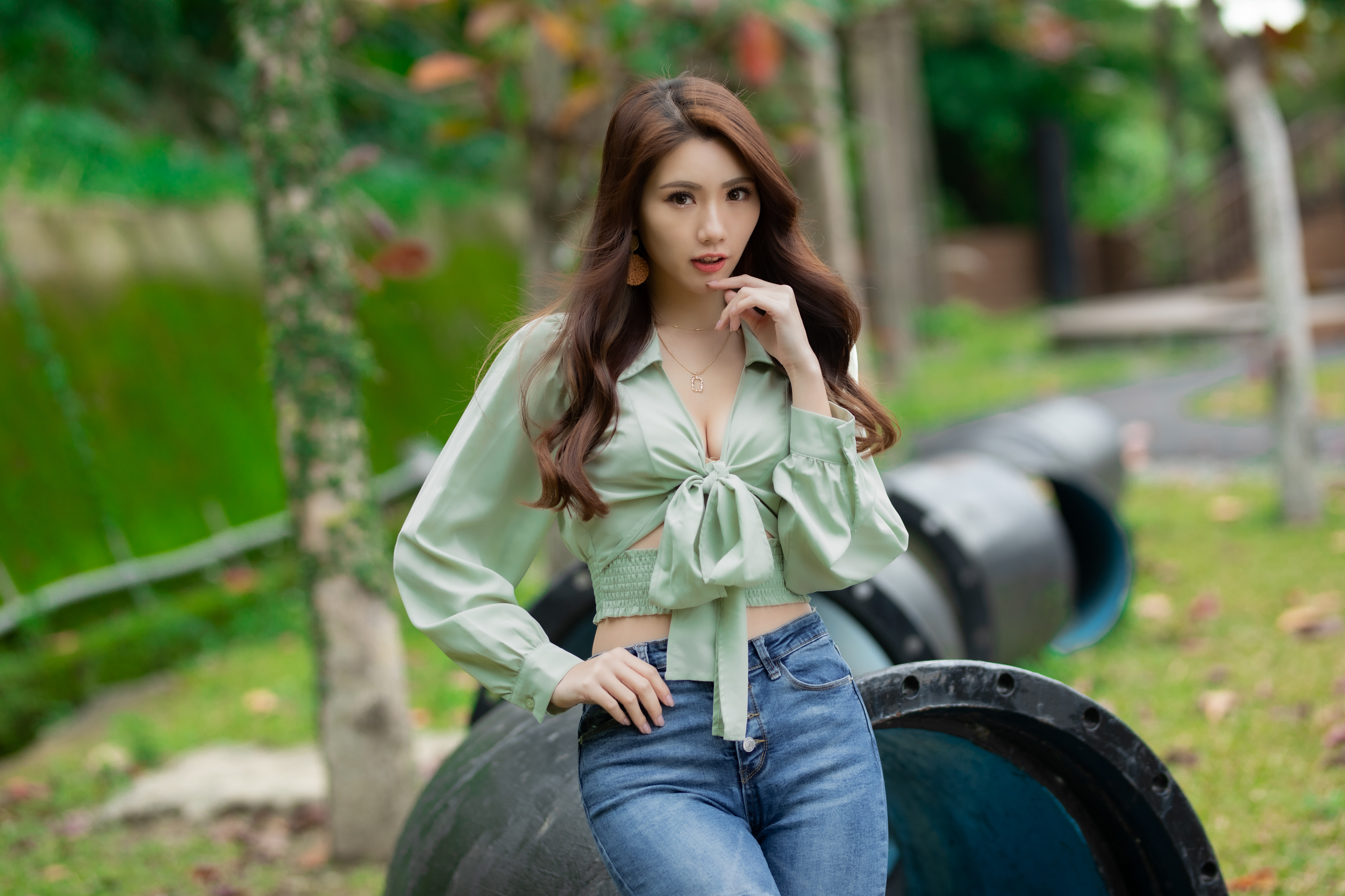 People 3840x2560 Asian model women women outdoors long hair brunette depth of field jeans blouses earring leaning necklace grass poles blurred blurry background cleavage looking at viewer