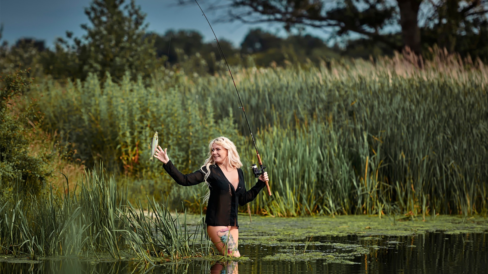 People 1920x1080 women model blonde long hair water lake long shirt black clothing fish fishing fishing rod smiling nature tattoo trees outdoors women outdoors animals in water standing partially clothed
