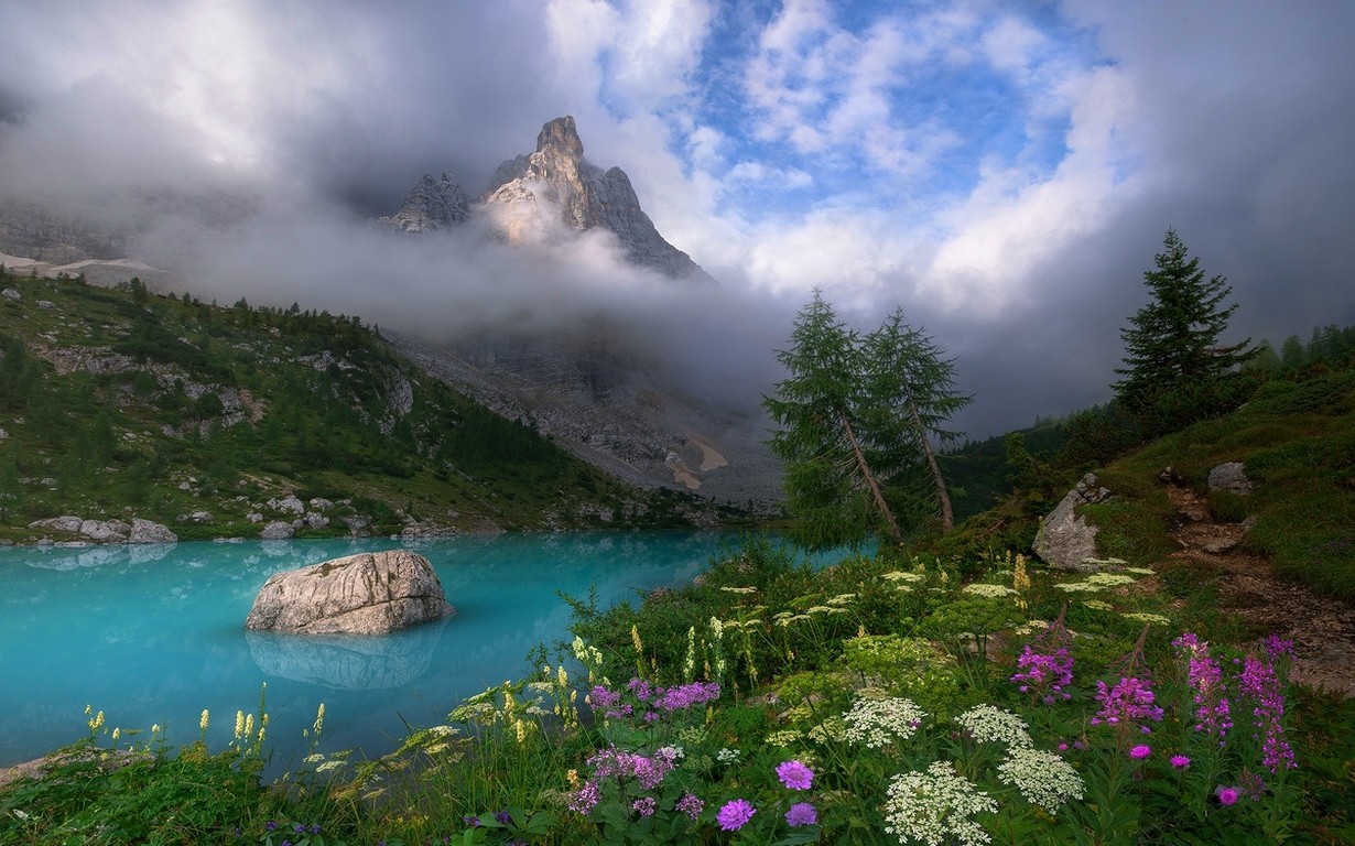 General 1230x768 Dolomites Italy spring mist lake wildflowers clouds turquoise water trees grass sunset sky mountains landscape
