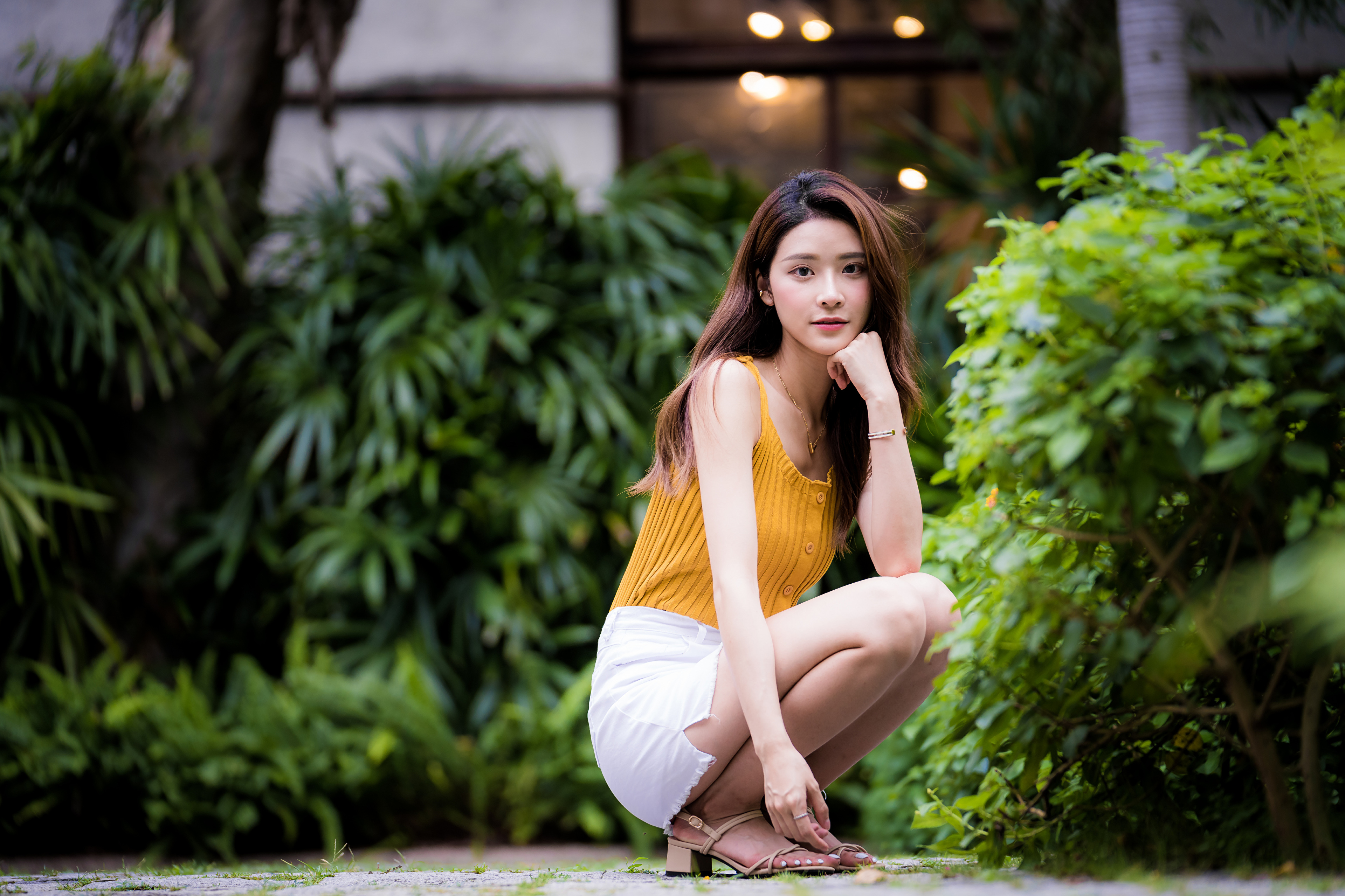 People 3840x2559 Asian model women long hair brunette white skirt yellow shirt barefoot sandal bushes depth of field looking at viewer squatting trees