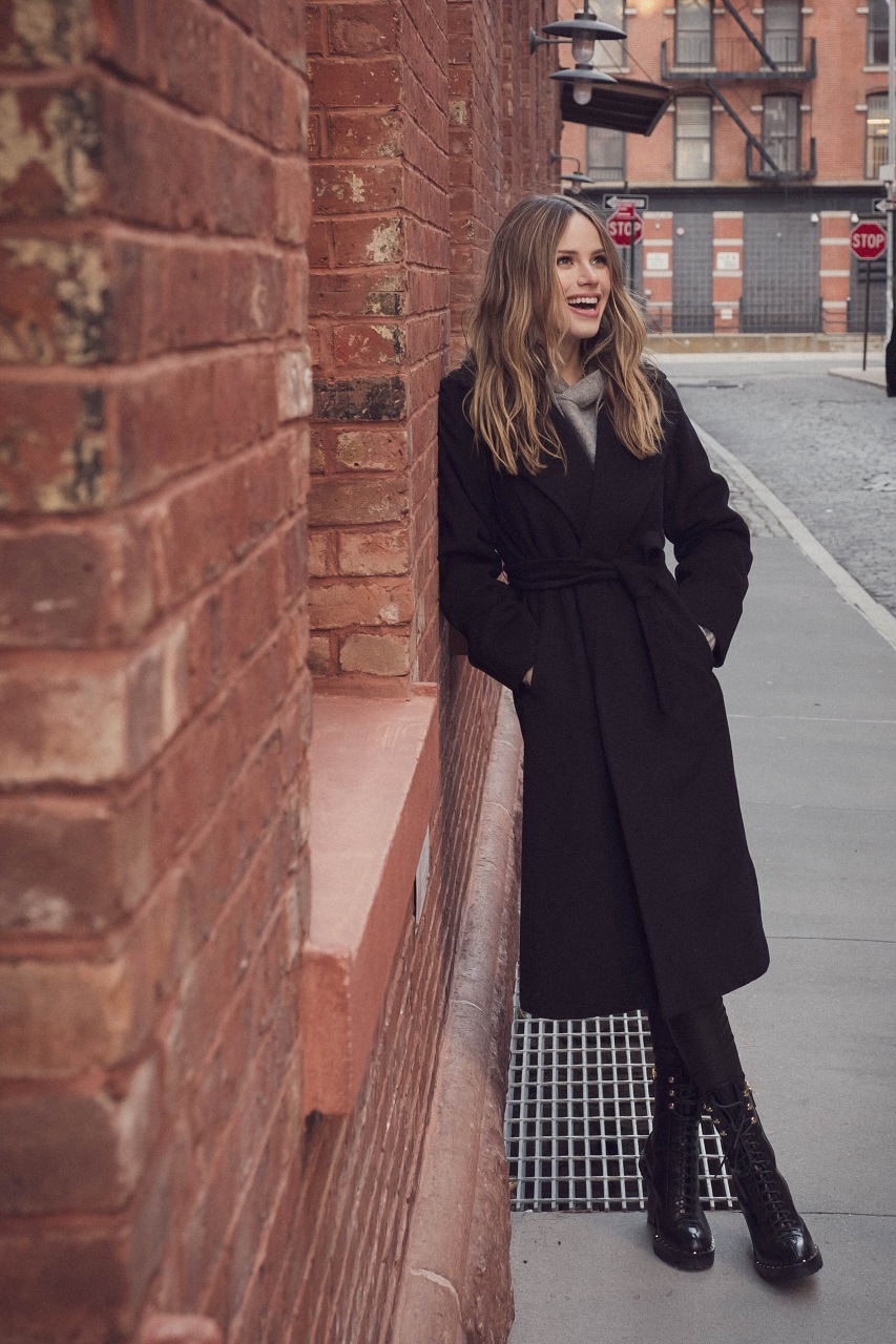 People 853x1280 Halston Sage women actress black coat legs crossed public long hair coats hands in pockets boots black boots women outdoors standing American women fashion street view laughing bricks outdoors glamour leather boots