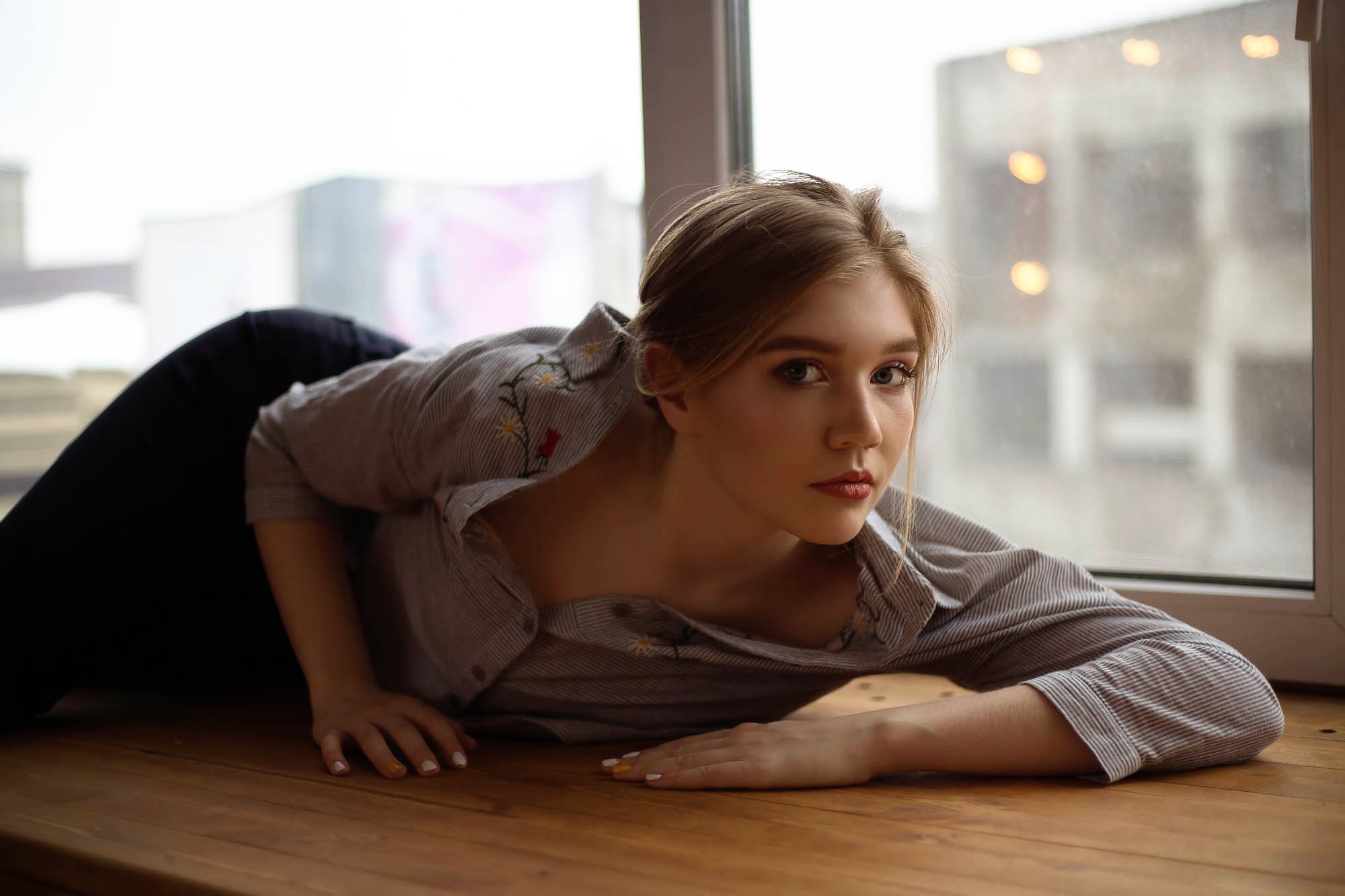 People 2000x1333 window face women model lying on front blonde red lipstick on table shirt looking at viewer makeup black pants painted nails closed mouth lying down gray eyes wooden surface
