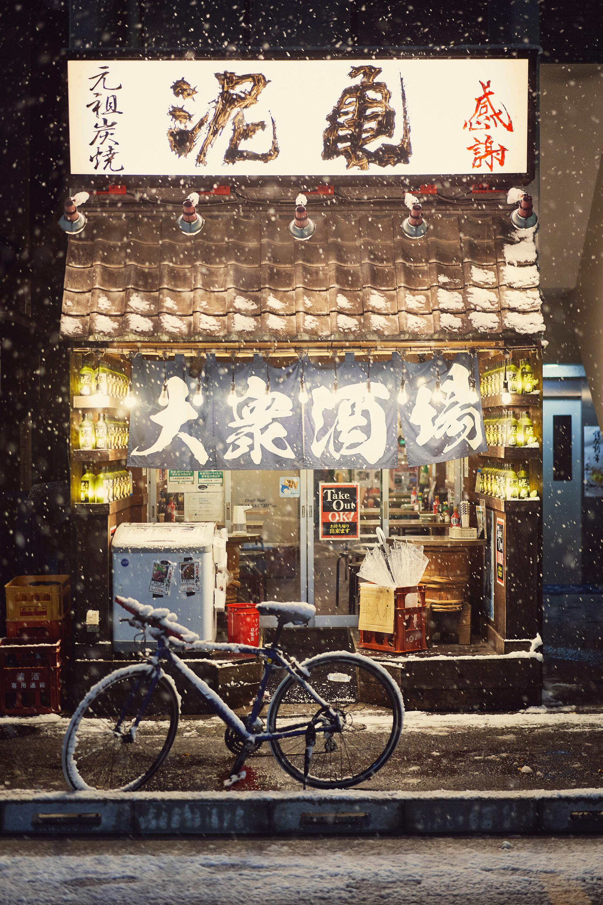 General 1937x2906 building urban city portrait display night Japan winter snow street bicycle stores snowing