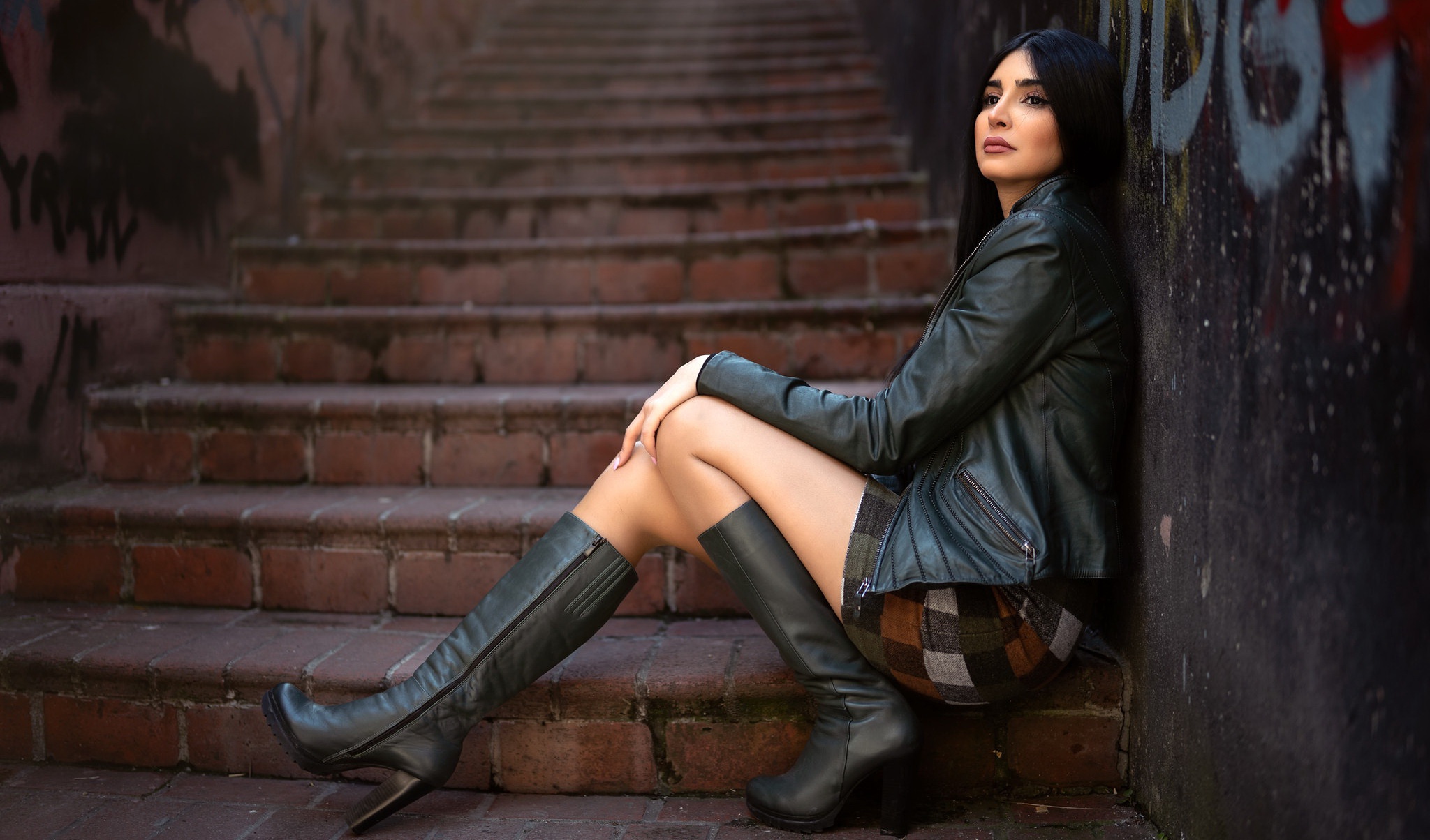 People 2048x1204 women model women outdoors urban sitting black hair makeup leather jacket stairs thighs boots heels high heeled boots looking into the distance dark hair hand on leg leather boots