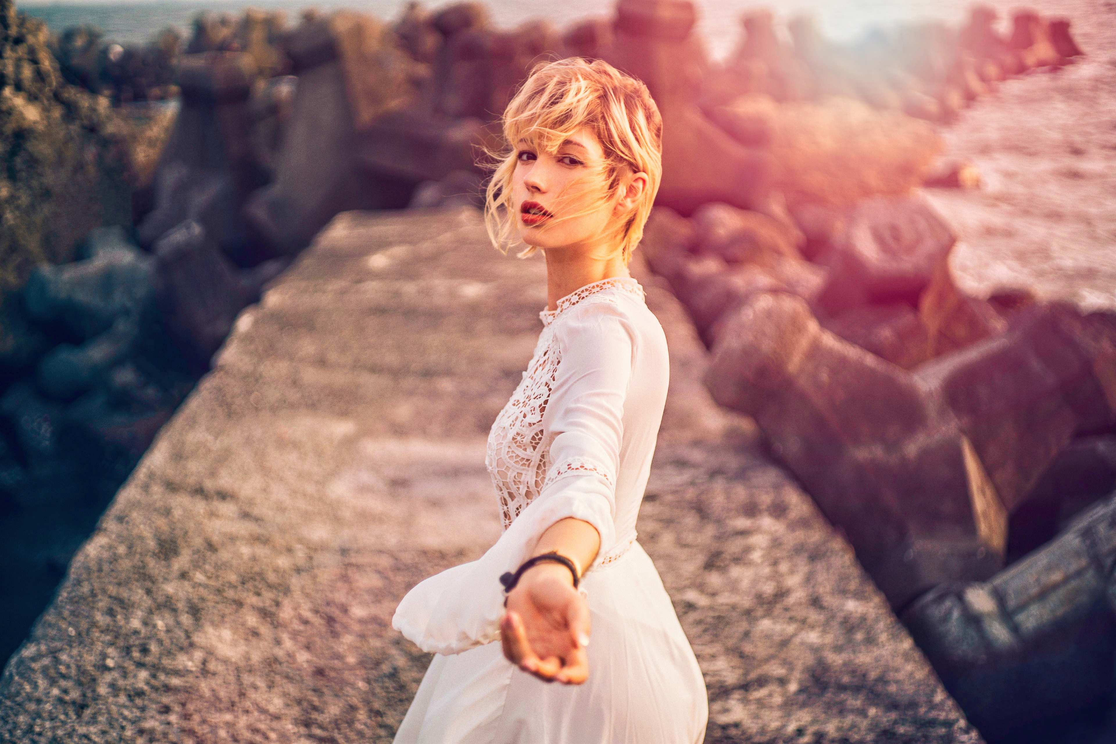 People 3840x2560 women women outdoors warm colors warm light water rocks blonde hand gesture looking at viewer photography depth of field white dress sunlight
