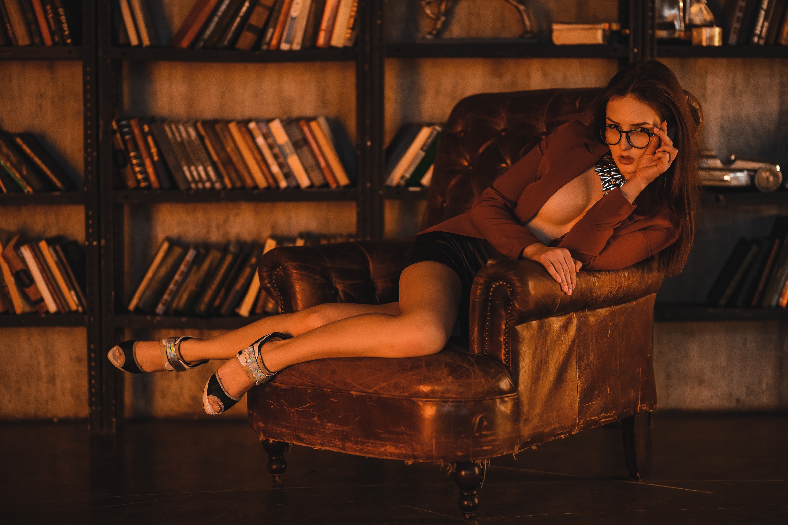 People 2560x1707 Alina Cortez women model brunette portrait looking at viewer women with glasses glasses sitting couch necklace books bookcase depth of field coats miniskirt leather skirts no bra open clothes heels indoors women indoors Ilya Pistoletov touching glasses