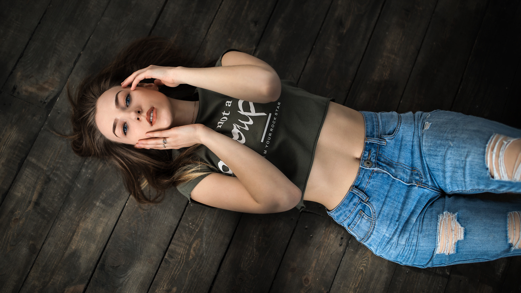 People 2000x1125 women top view brunette torn jeans blue eyes lying on back belly wooden surface portrait touching face short tops looking at viewer Alexey Osipkin