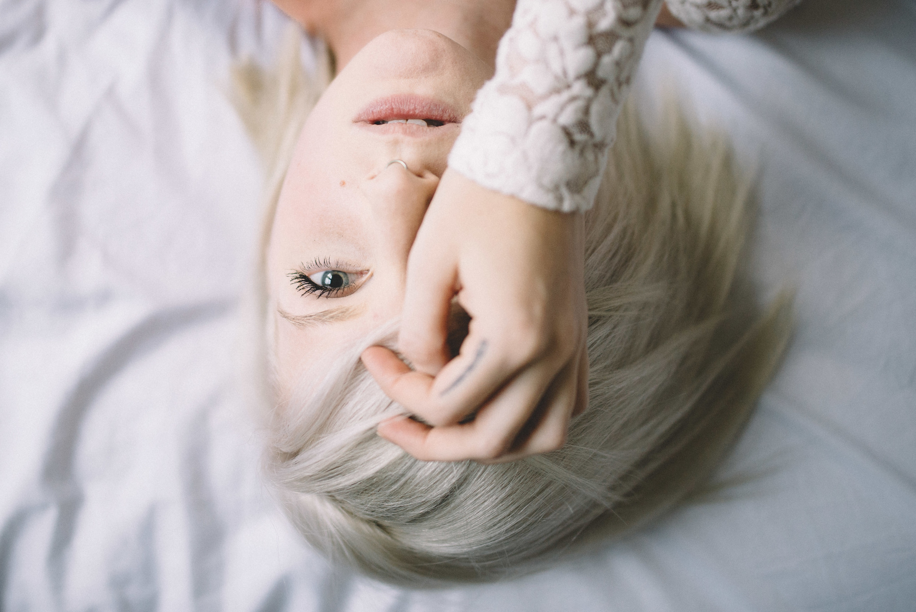 People 1797x1200 blonde women model pierced septum face gray eyes open mouth hand on face short hair women indoors portrait closeup bokeh lying on back top view looking at viewer
