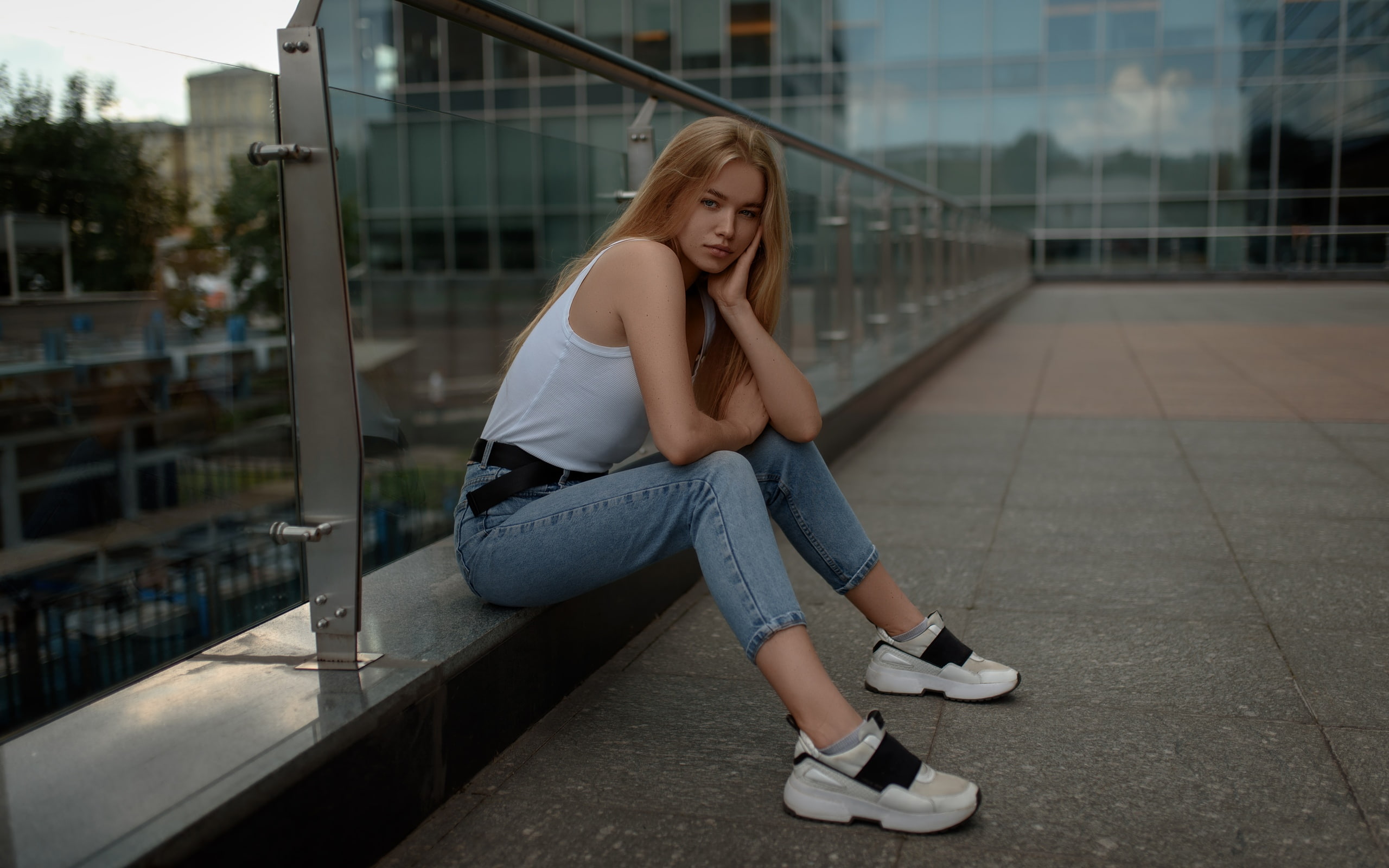 People 2560x1600 women model blonde long hair looking at viewer touching face tank top white tops jeans glass sitting sneakers side view depth of field building portrait outdoors women outdoors