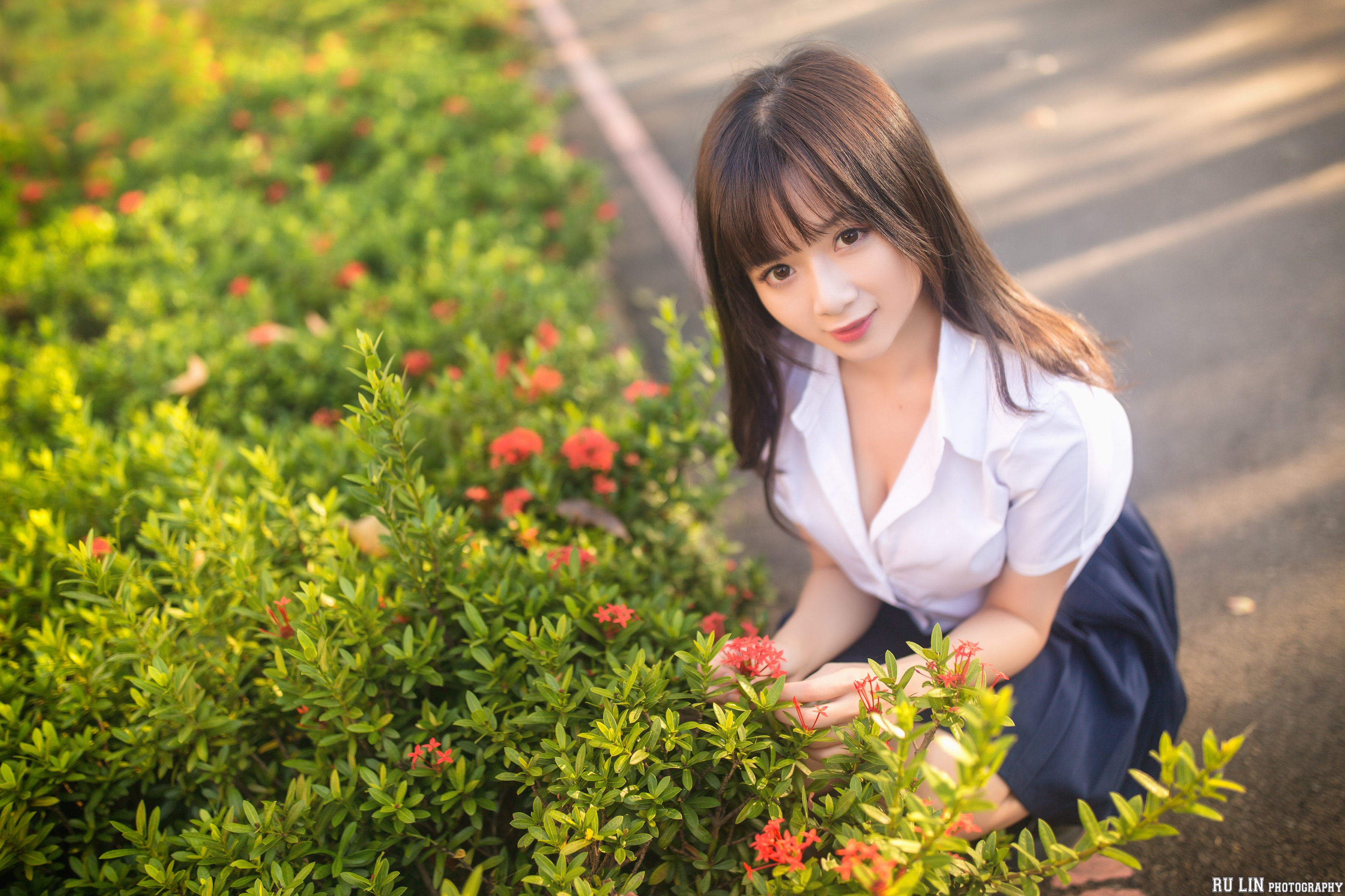 People 3600x2400 Winnie Qian women Asian model looking at viewer smiling brunette bangs long hair brown eyes shirt bokeh cleavage skirt flowers plants depth of field squatting portrait high angle outdoors women outdoors Chinese