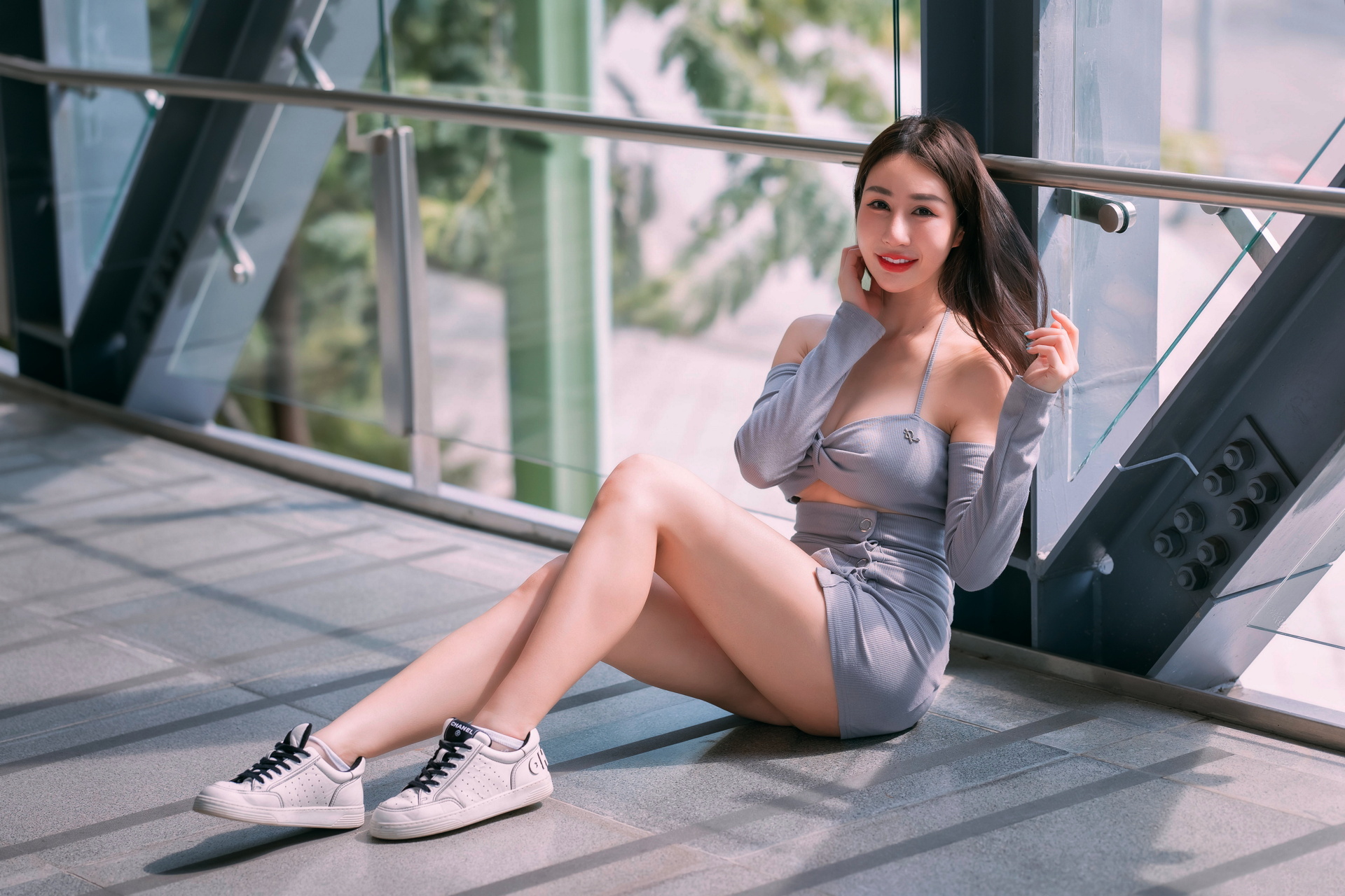 People 1920x1280 Asian model women long hair dark hair sitting grey skirt grey tops sneakers leaning iron railing window depth of field white sneakers legs socks sunlight miniskirt skirt cleavage big boobs bare shoulders smiling red lipstick on the ground looking at viewer