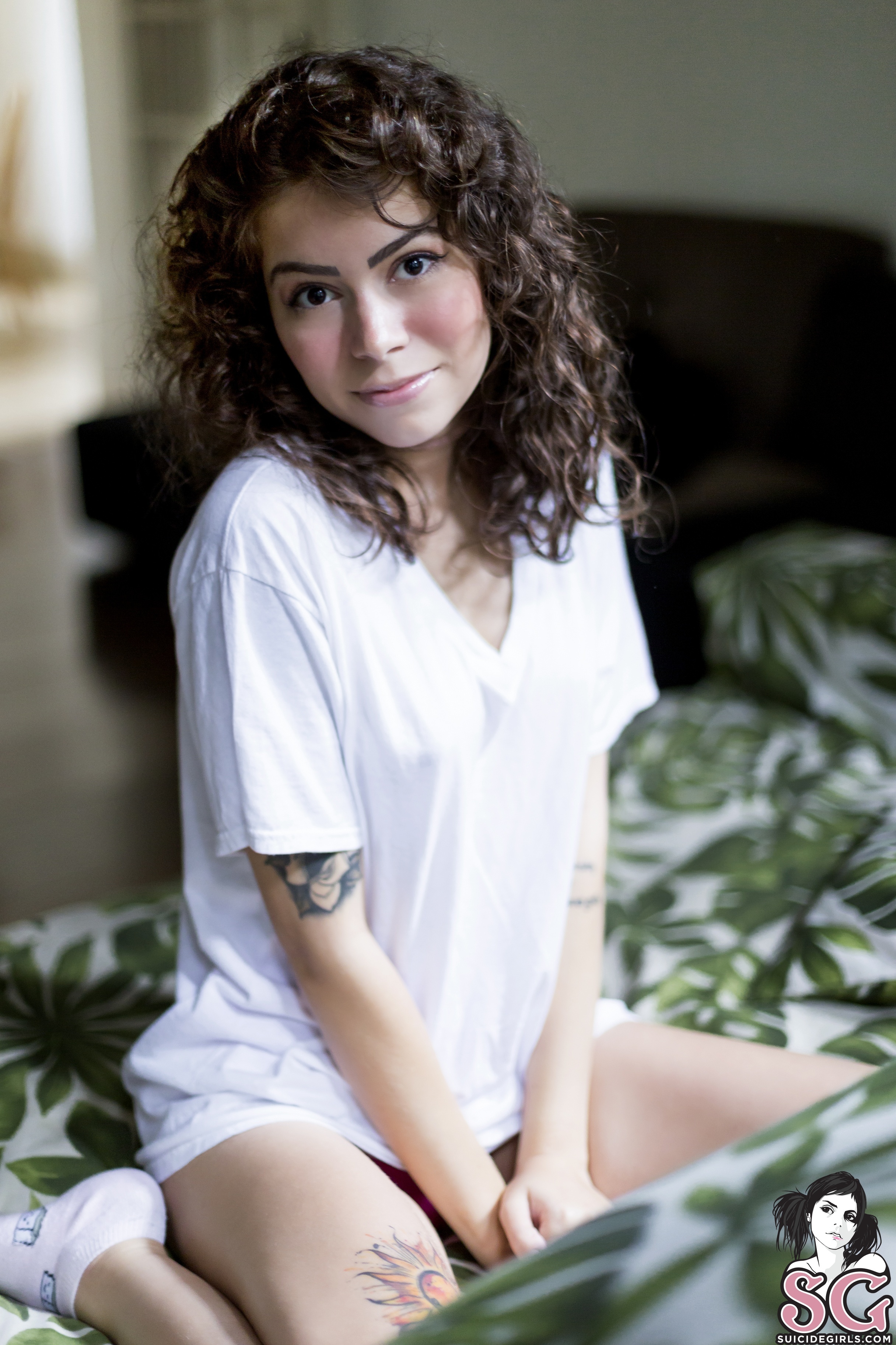 People 2432x3648 Suicide Girls women brunette tattoo T-shirt socks couch plants Dinhasun  room white socks short socks bent legs white t-shirt curly hair shoulder length hair looking at viewer watermarked portrait display