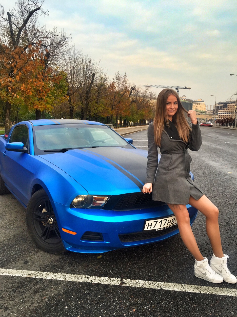 People 960x1280 model brunette women smiling Sonya Temnikova women with cars women outdoors holding hair sitting blue cars looking at viewer grey coat coats Anna Kasparova portrait display overcoats one arm up Caucasian car Ford Ford Mustang muscle cars American women