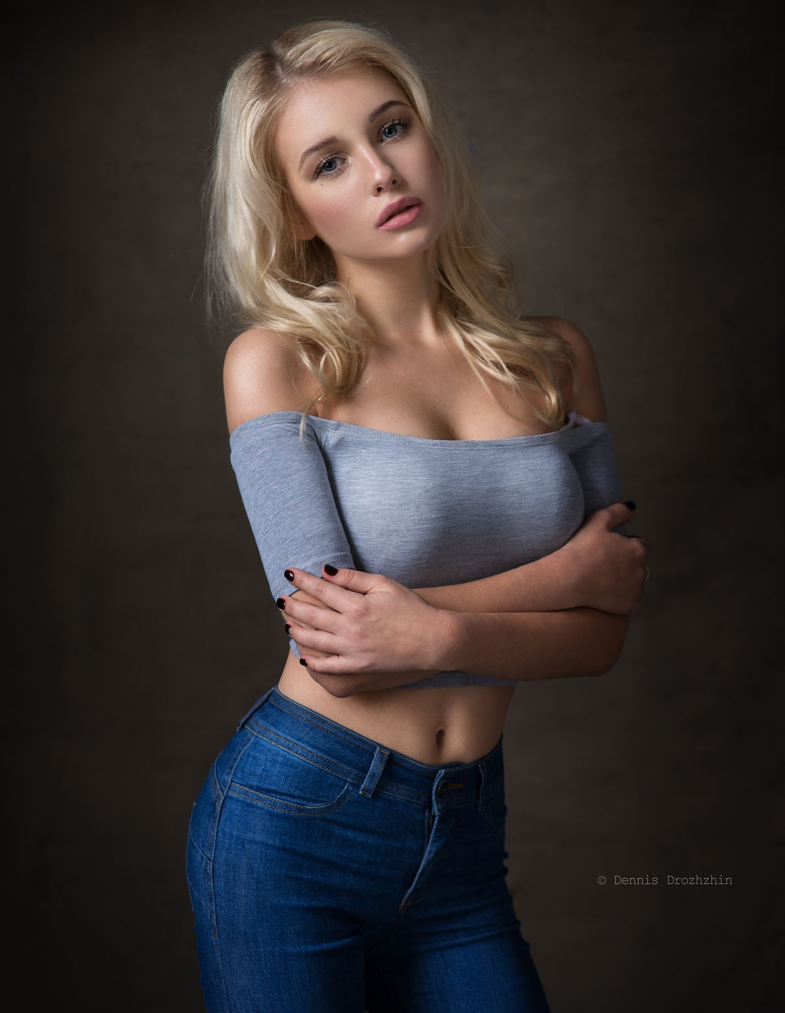 People 1551x2000 Dennis Drozhzhin women blonde long hair straight hair blue eyes looking at viewer juicy lips lipstick blushing blouses bare shoulders grey clothing jeans denim painted nails black nails jewelry rings simple background grey tops watermarked makeup bare midriff arms crossed model studio