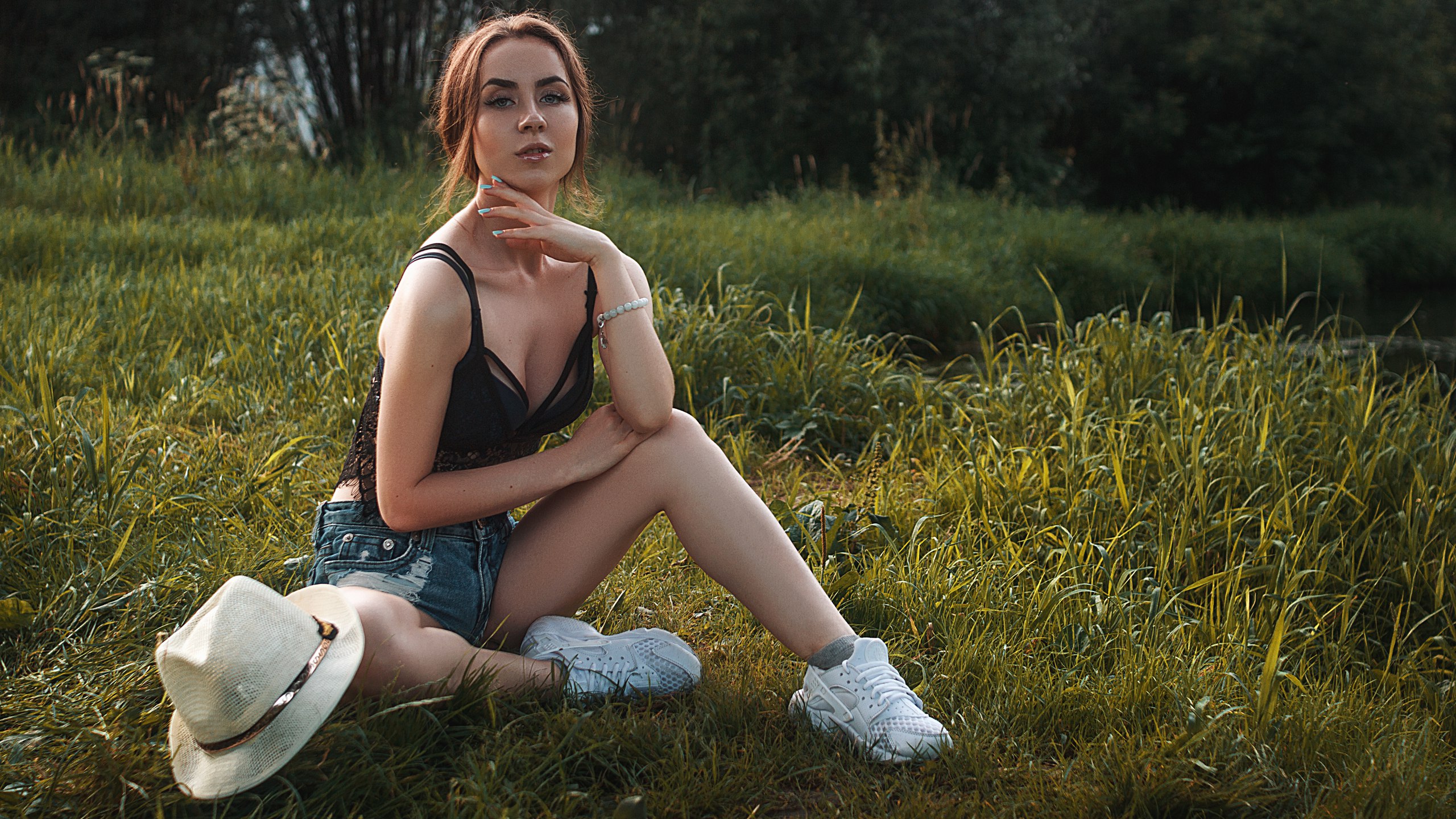 People 2560x1440 women model brunette looking at viewer painted nails grass depth of field outdoors sneakers sitting jean shorts hat black top cleavage on the floor women outdoors Vlad Popov